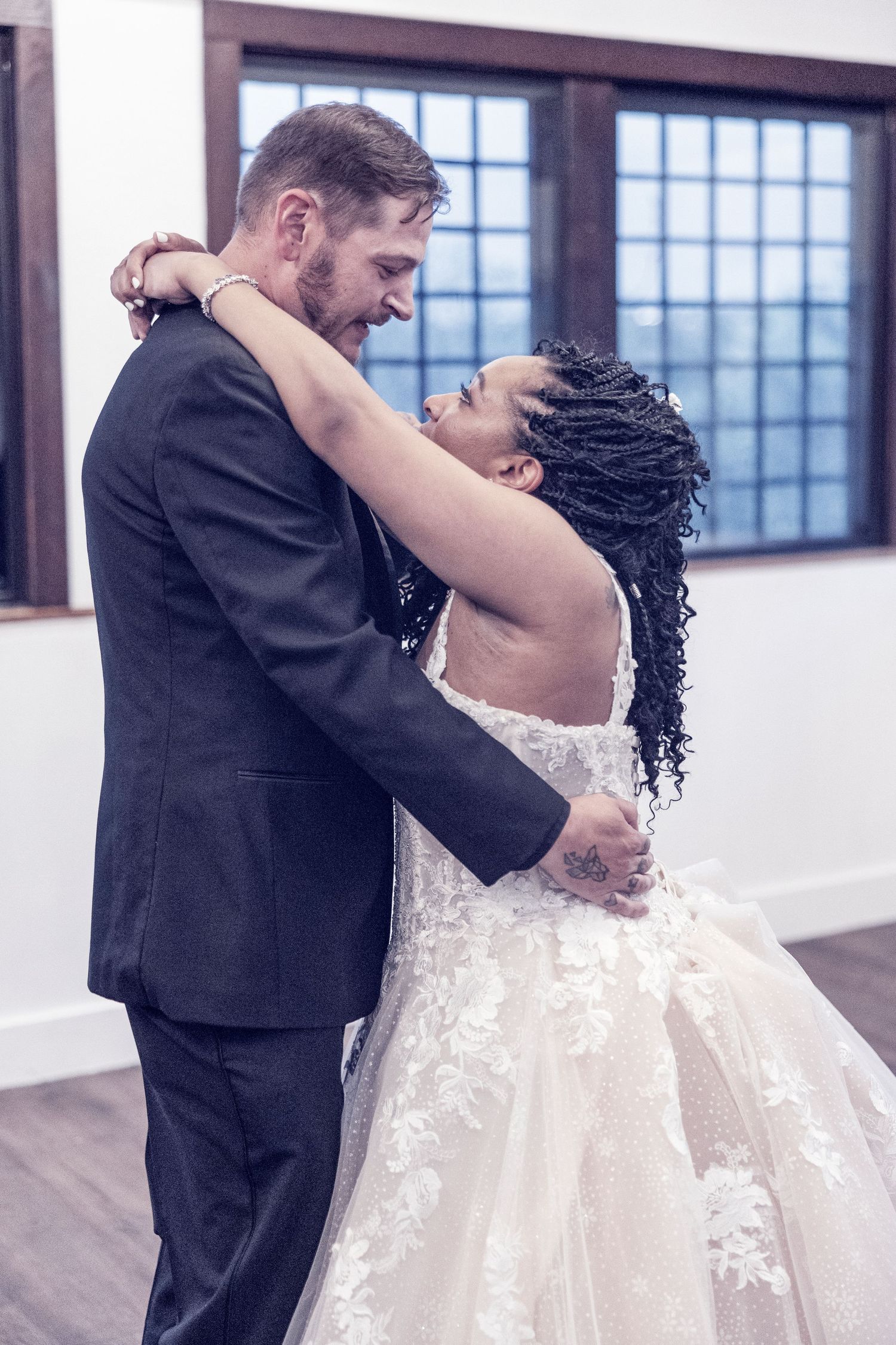 A romantic first dance moment between newlyweds, with the bride in a flowing white lace gown and groom in black suit.