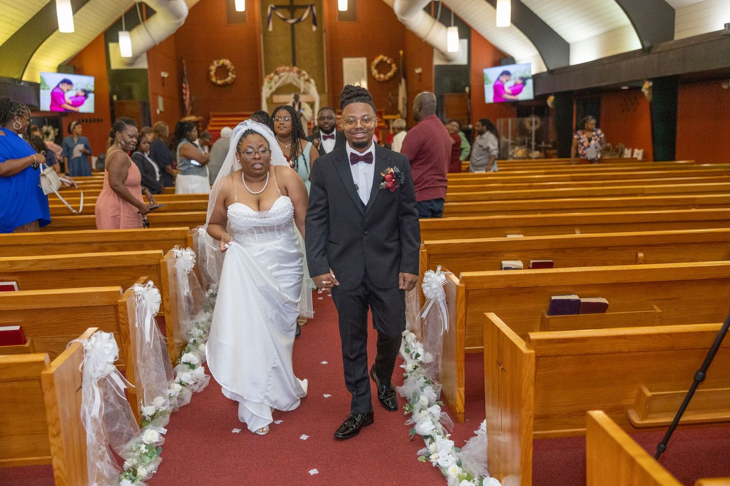 A joyous wedding ceremony unfolds in a church with wooden pews and stained glass windows.