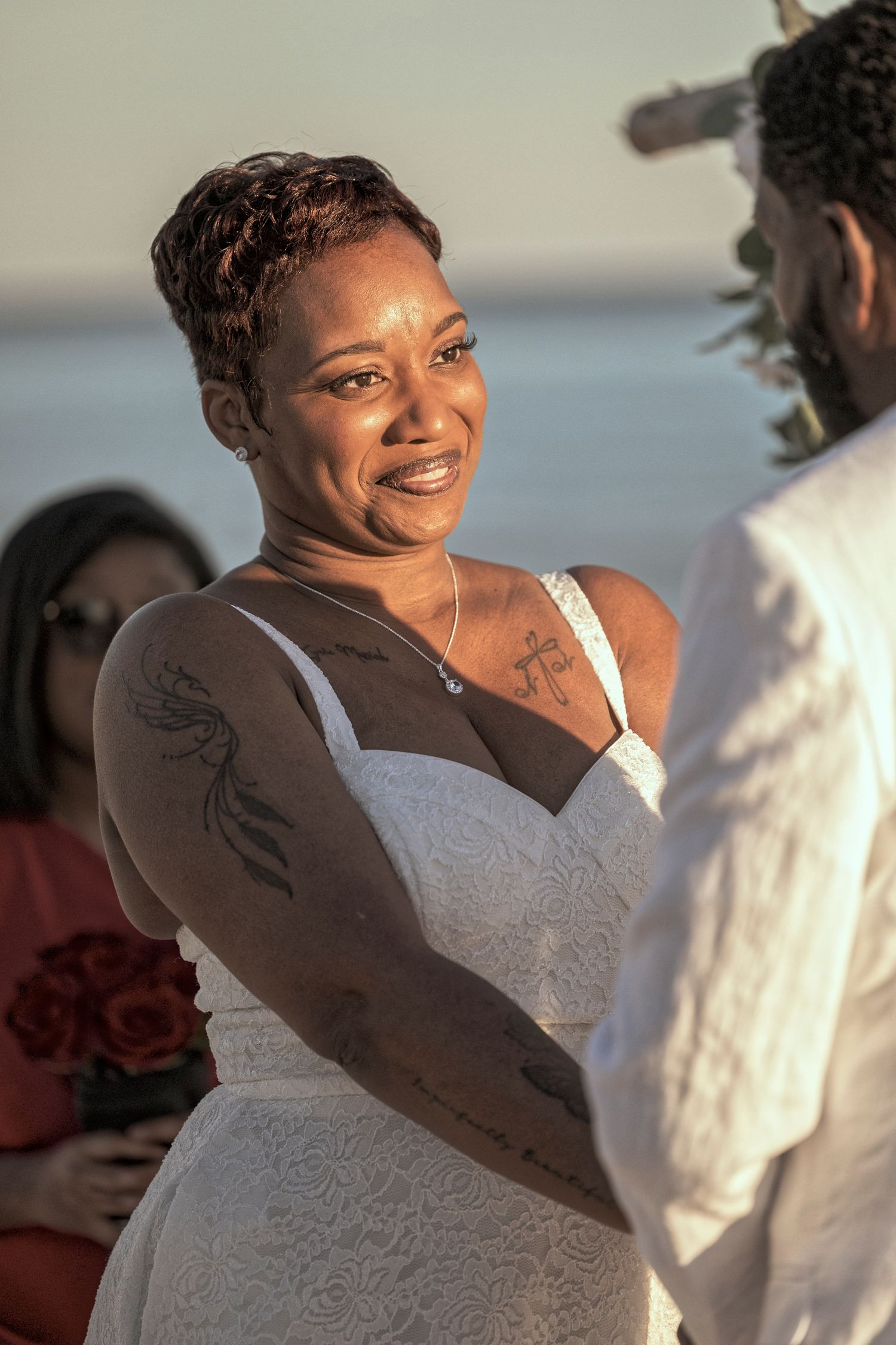 A couple shares a joyful dance moment at a sunset beach wedding celebration.