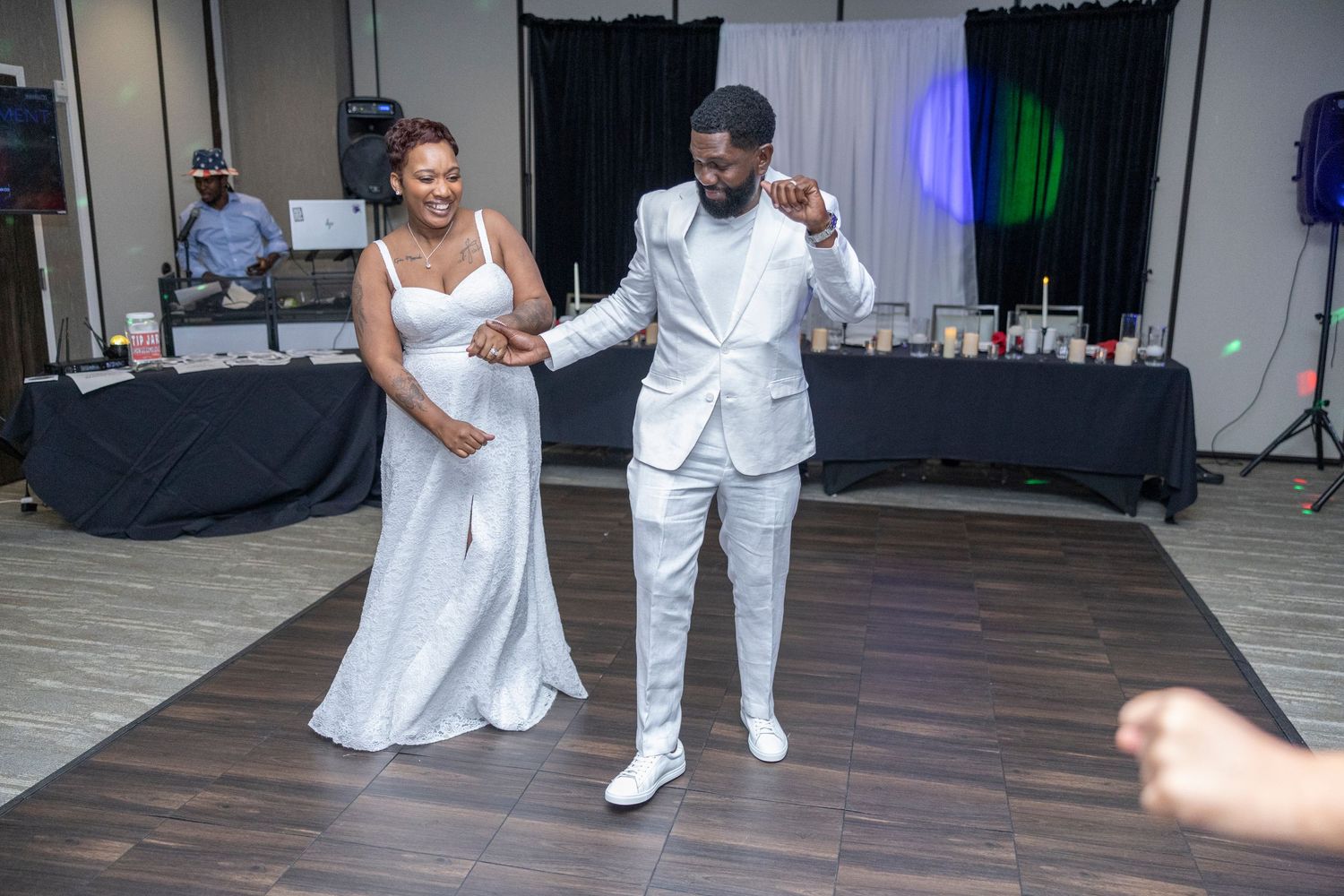 A couple shares their first dance at their wedding reception, with the bride in white and groom in an all-white suit.