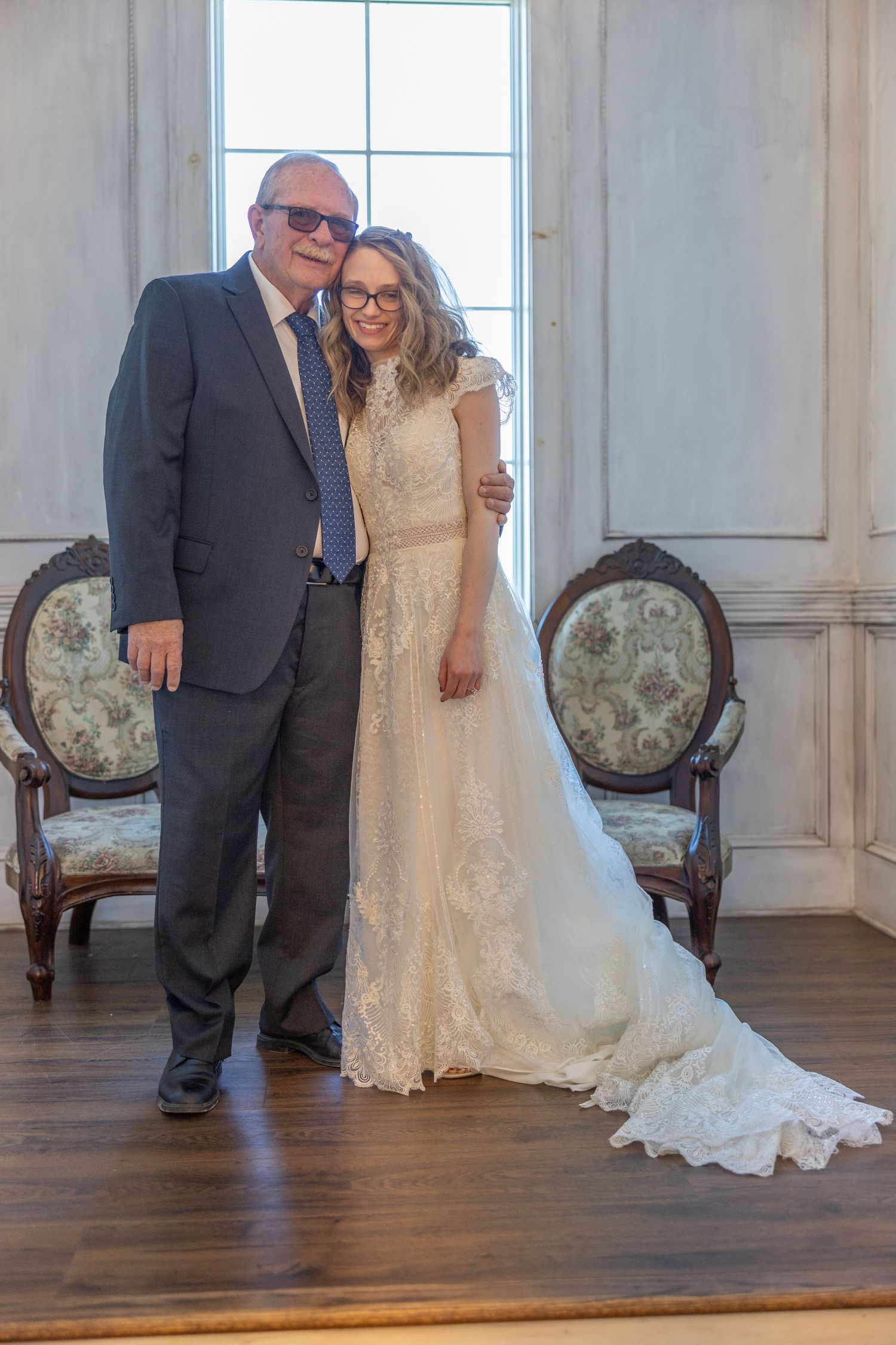 A wedding couple poses in a bright room with ornate vintage chairs and hardwood floors in a series of similar shots.