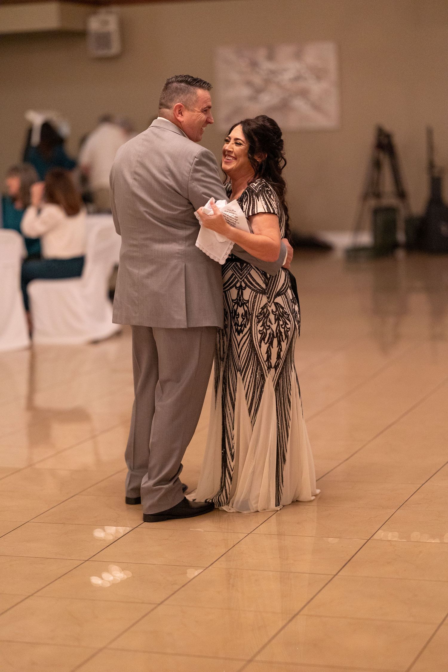 Couple sharing an intimate dance moment at wedding reception on wooden dance floor.