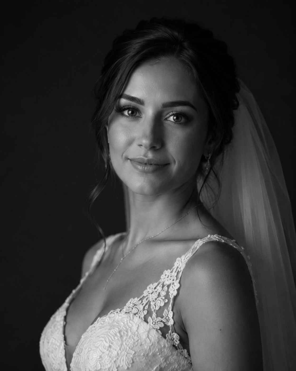 Black and white portrait of a beautiful bride wearing lace wedding gown and veil with soft romantic lighting.