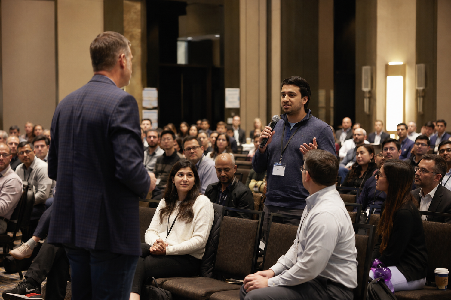 A conference attendee asks a question during an interactive Q&A session at a professional business event.