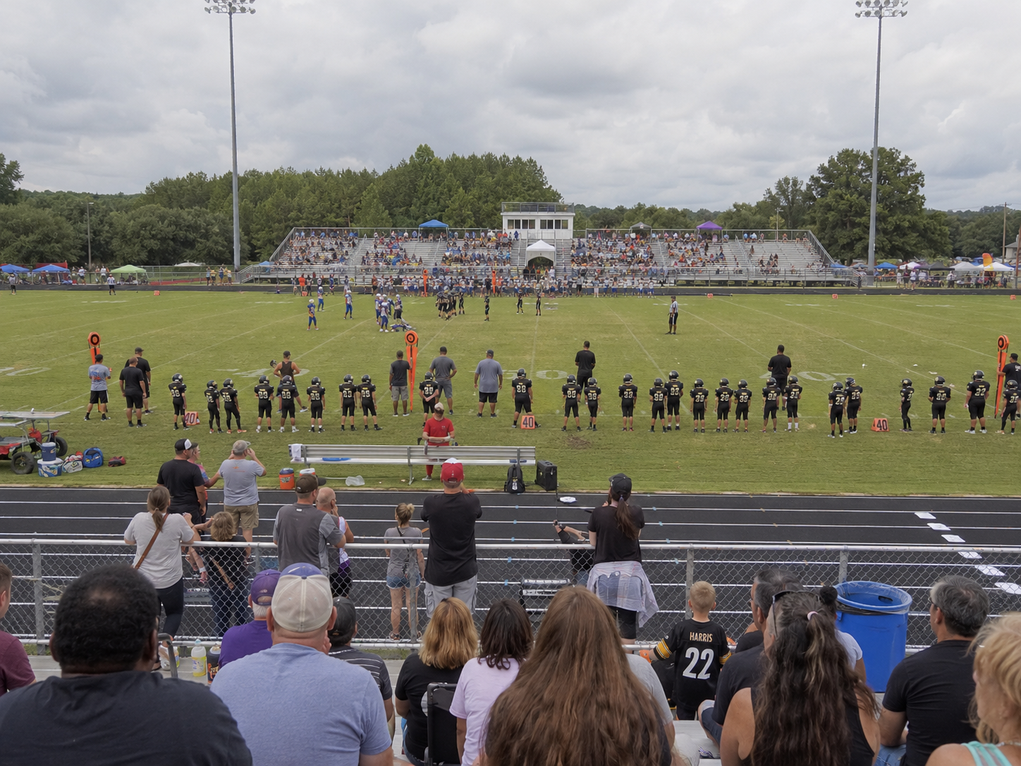Soccer teams line up on the field before a match at a packed outdoor stadium.