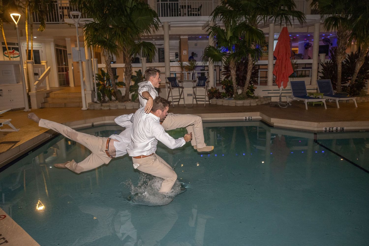A sequence of photos showing someone falling backwards into a swimming pool at night.