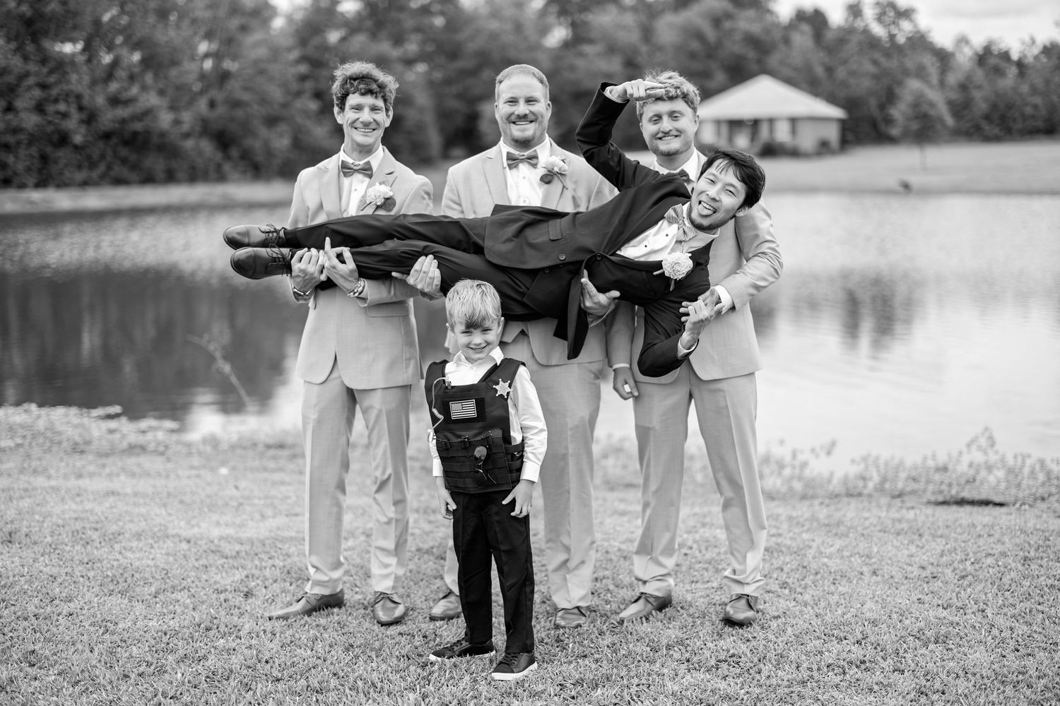 A vintage black and white photograph of a group of musicians with instruments posing by a lake.
