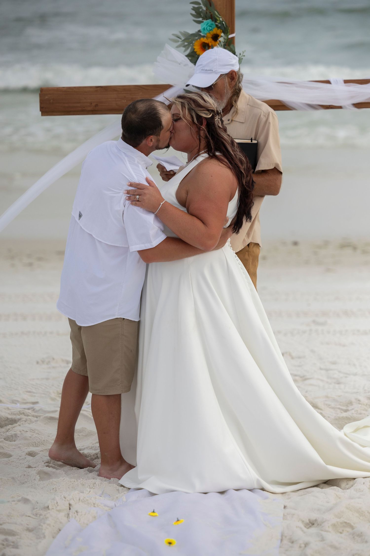 A couple shares a romantic moment on a sandy beach during their wedding ceremony.