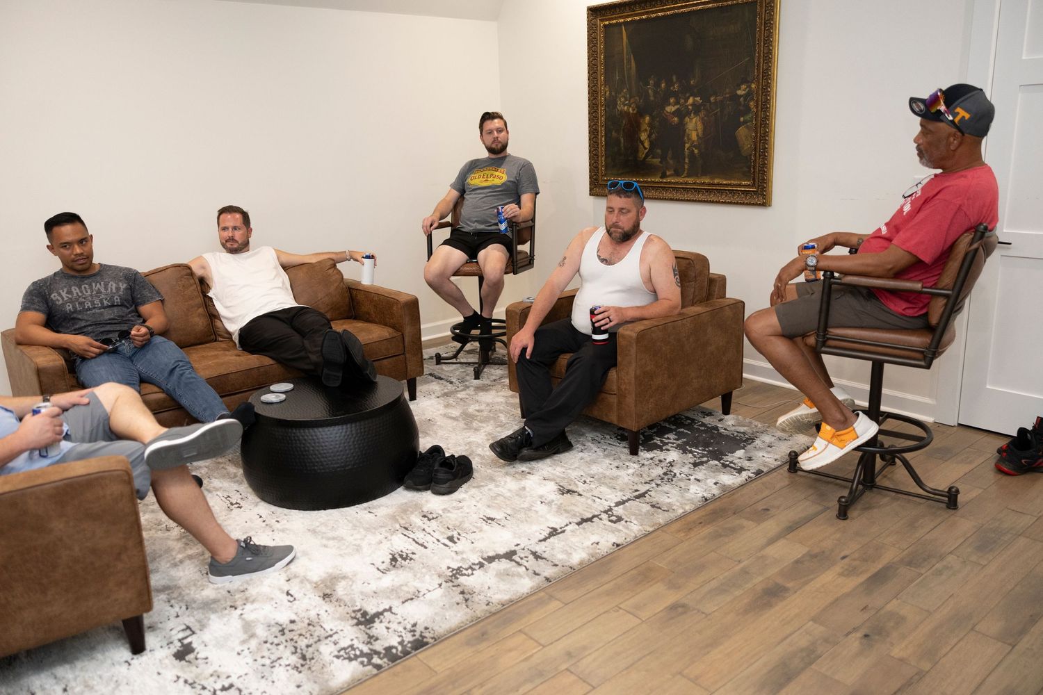 People sitting on brown leather couches in a living room during a casual gathering.