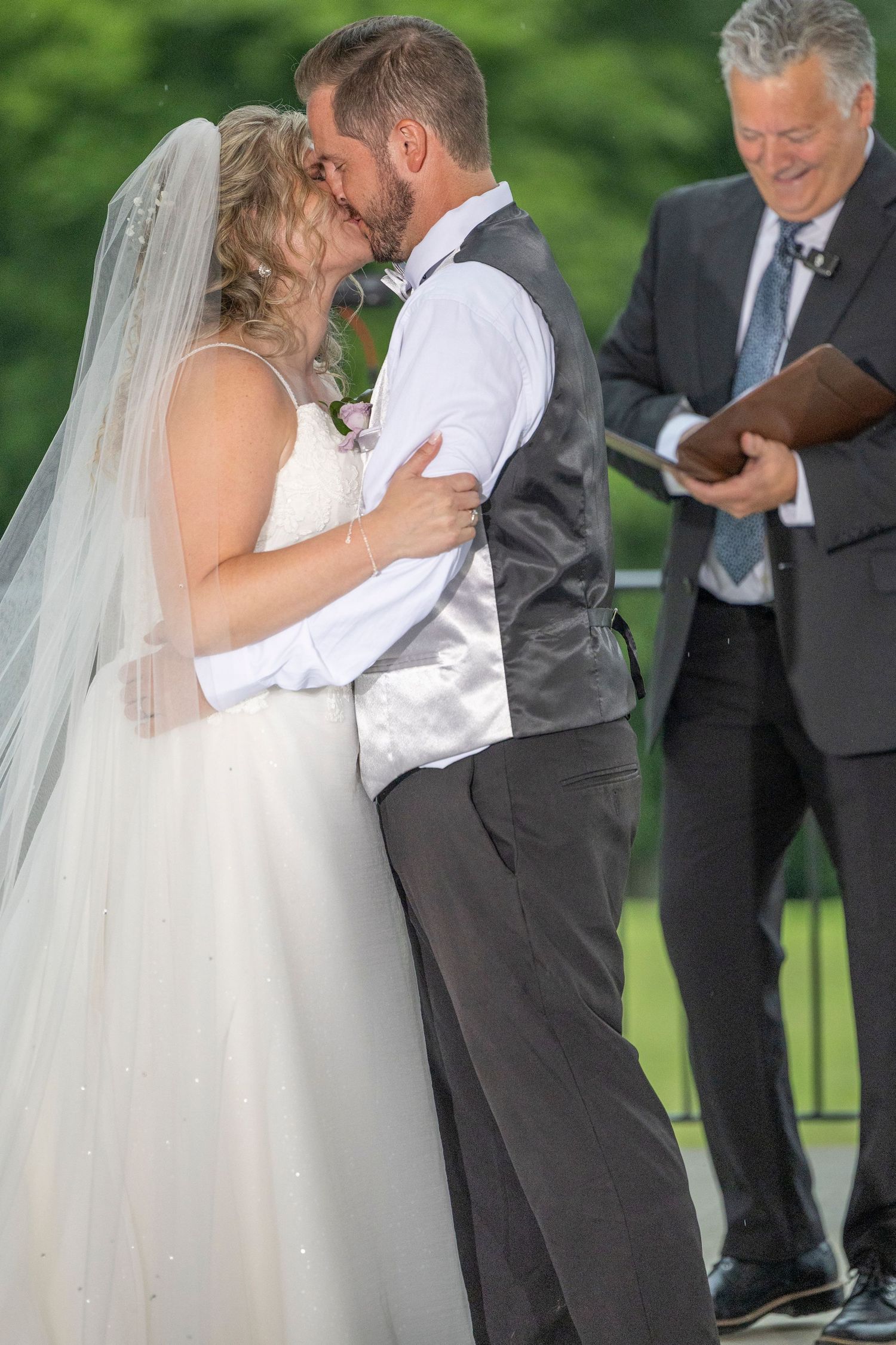 A sequence of wedding ceremony photos showing a couple sharing their first kiss as newlyweds outdoors.