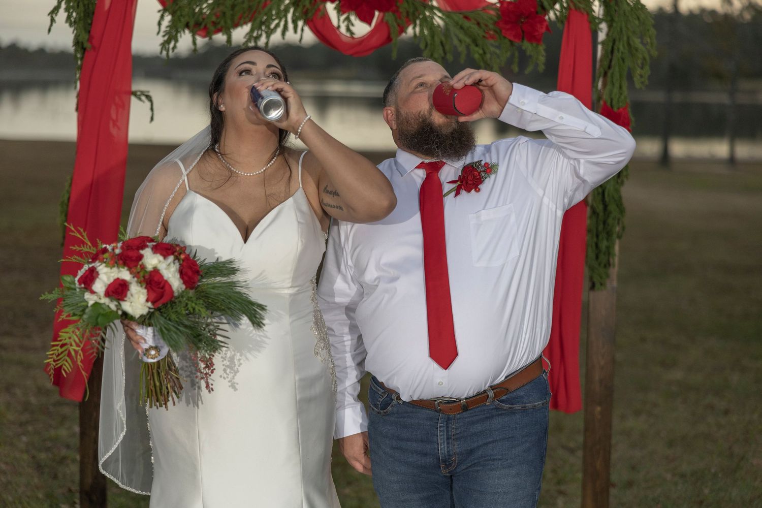 A couple shares a romantic moment outdoors surrounded by red ribbons and holiday greenery decorations.