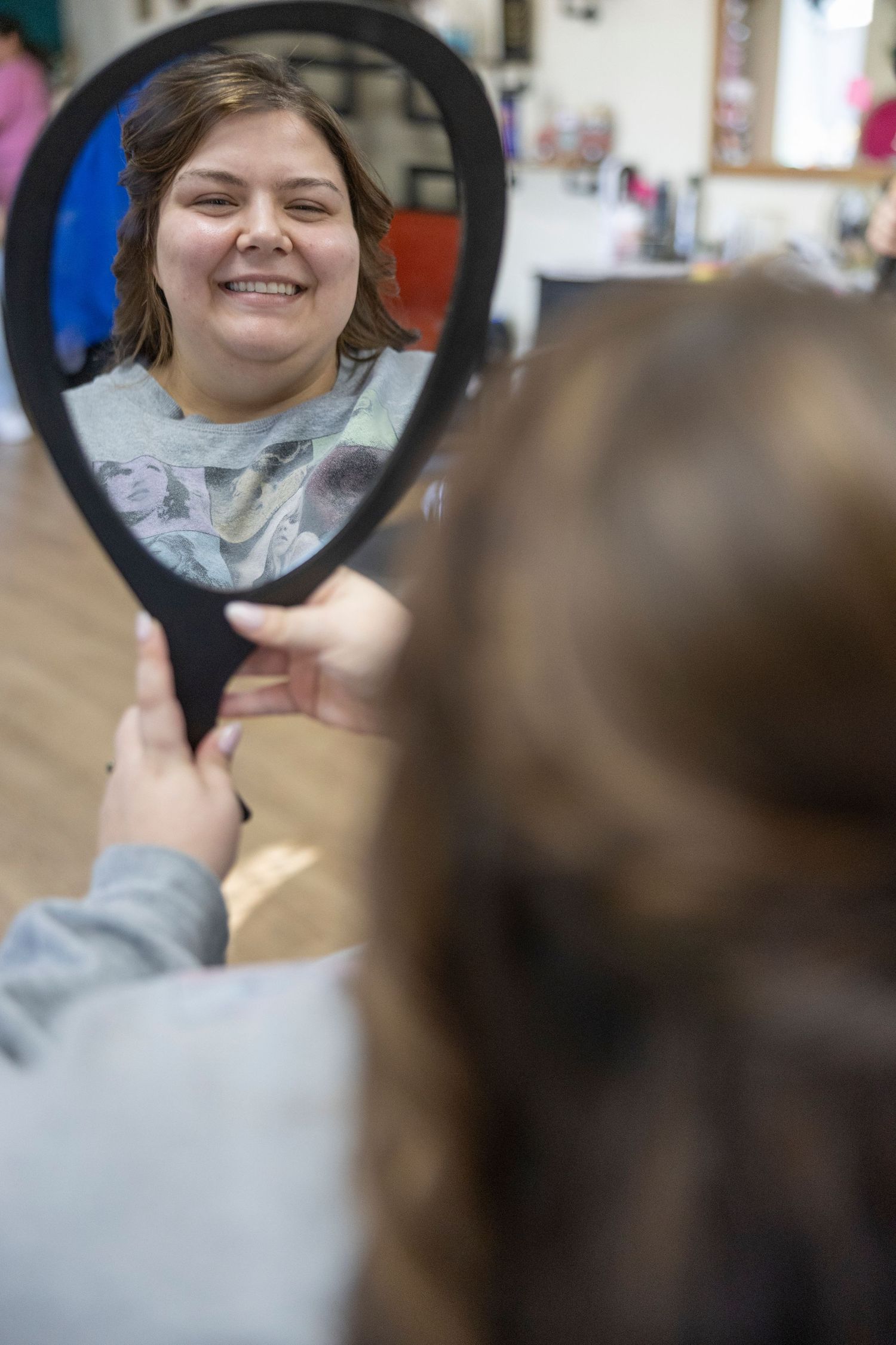 A series of circular mirror reflections showing someone with short hair and a grey shirt smiling in different angles.