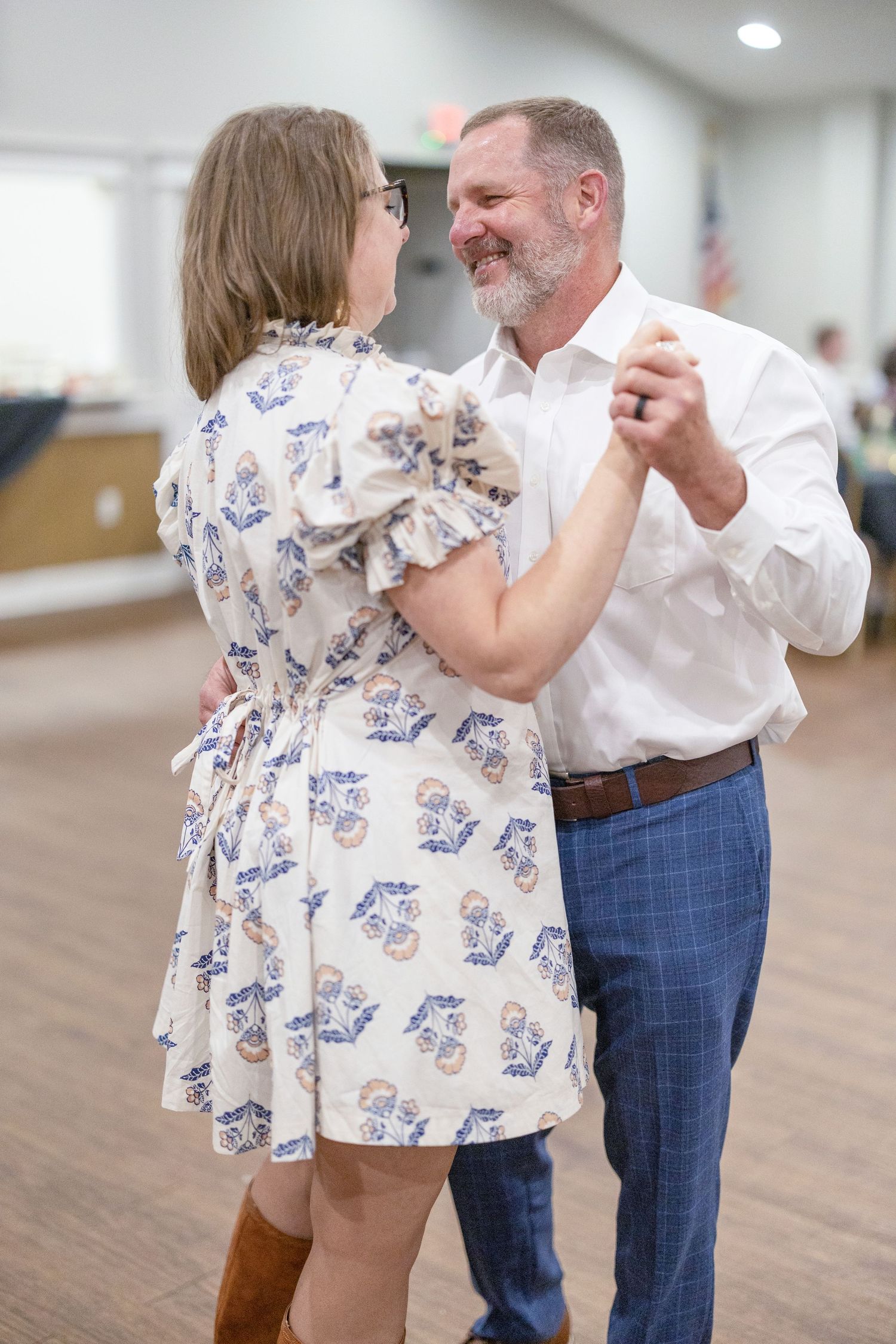 A heartwarming dance sequence between two people in a bright indoor space with wooden floors.