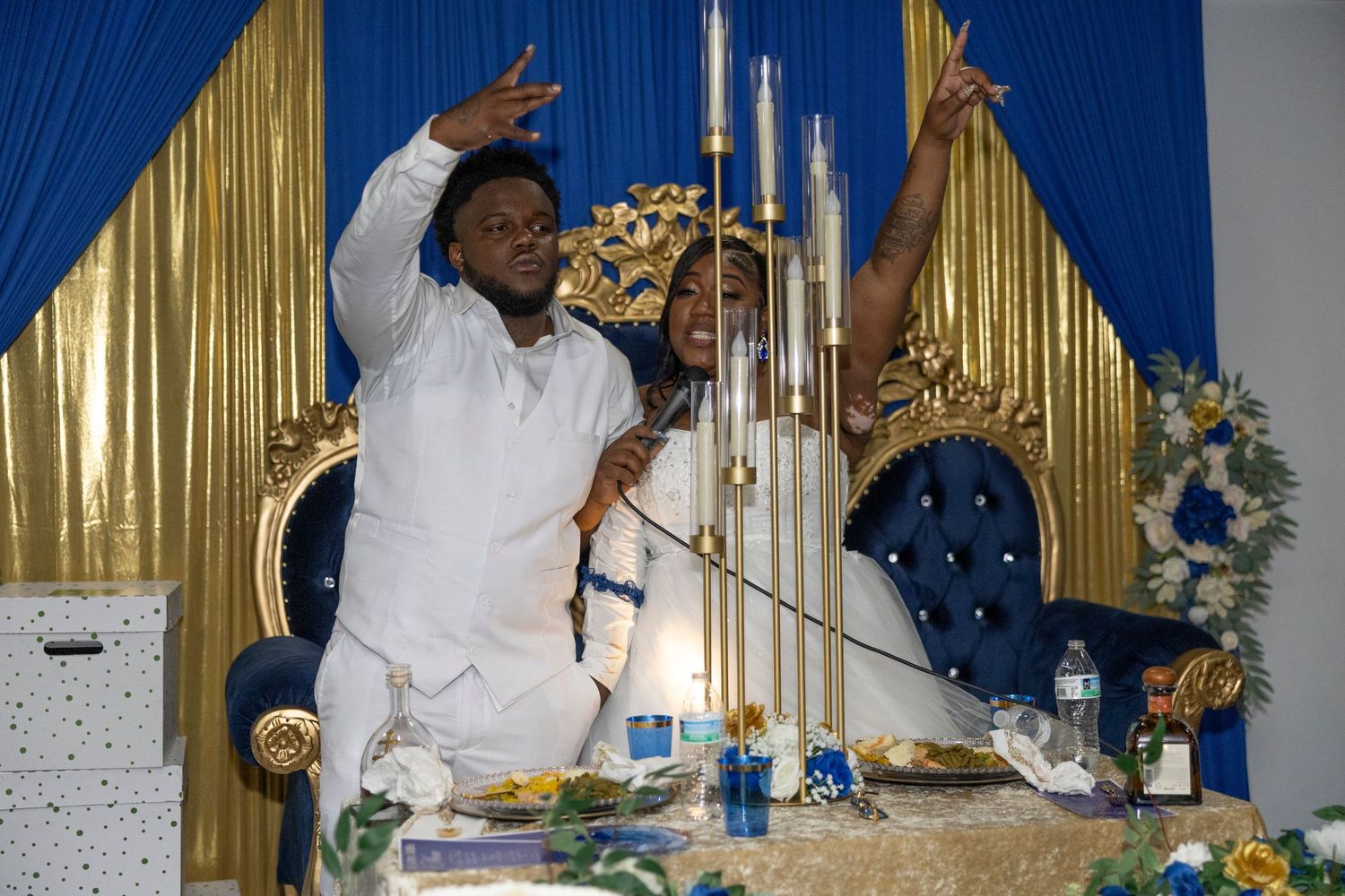 Couple celebrating at a wedding reception with candles and blue gold decor backdrop.