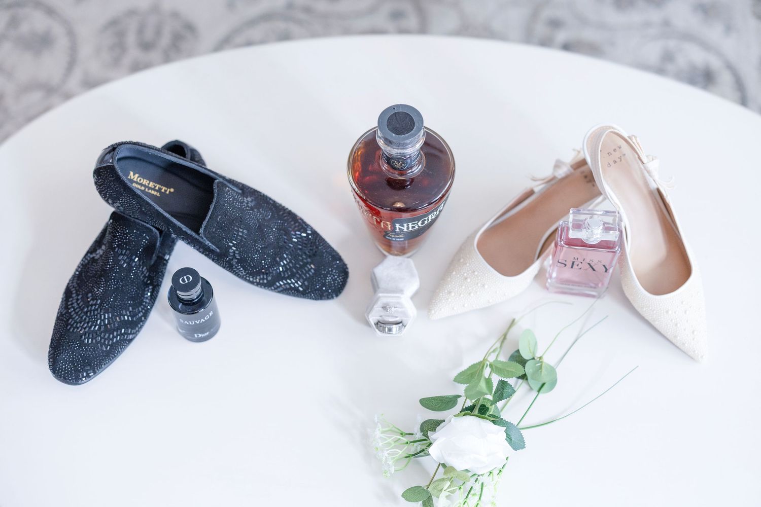 Nail polish bottles and manicure tools arranged with green plant leaves on a white surface.