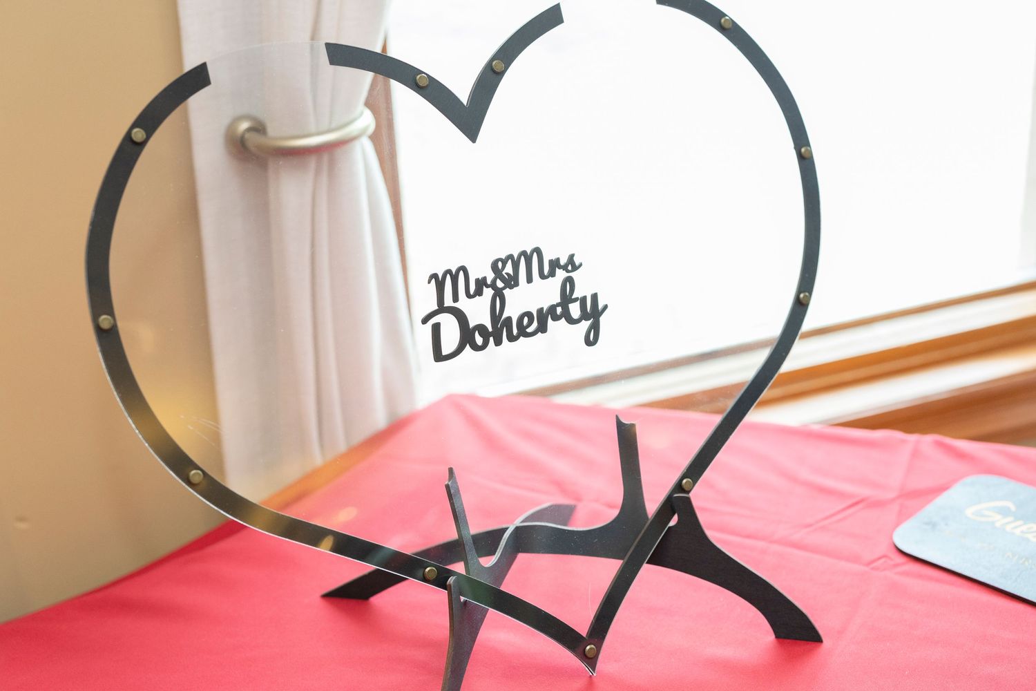 A black heart-shaped hanger with pink fabric visible in the background.
