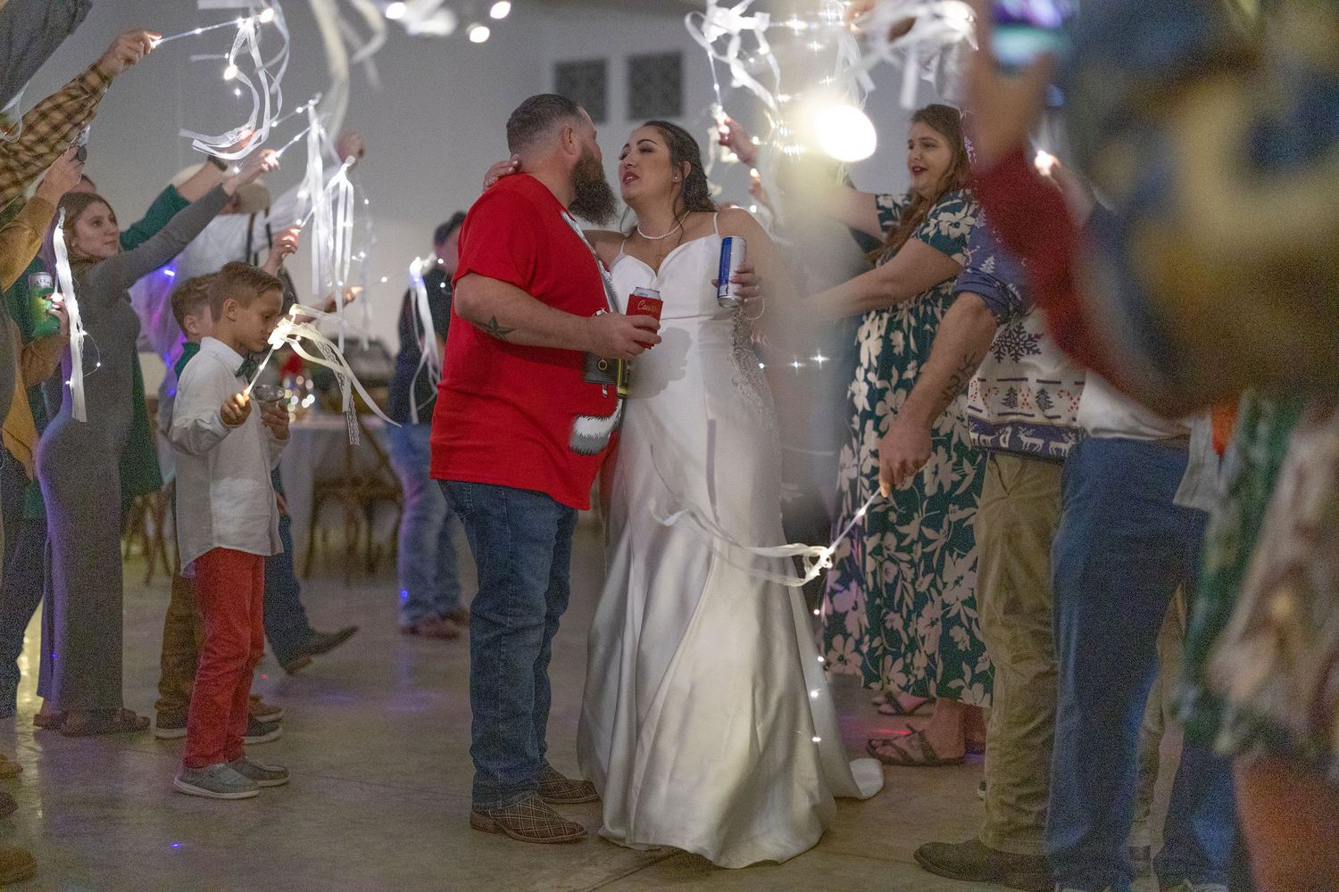 Wedding guests blow bubbles as the bride and groom walk through a festive outdoor reception celebration.