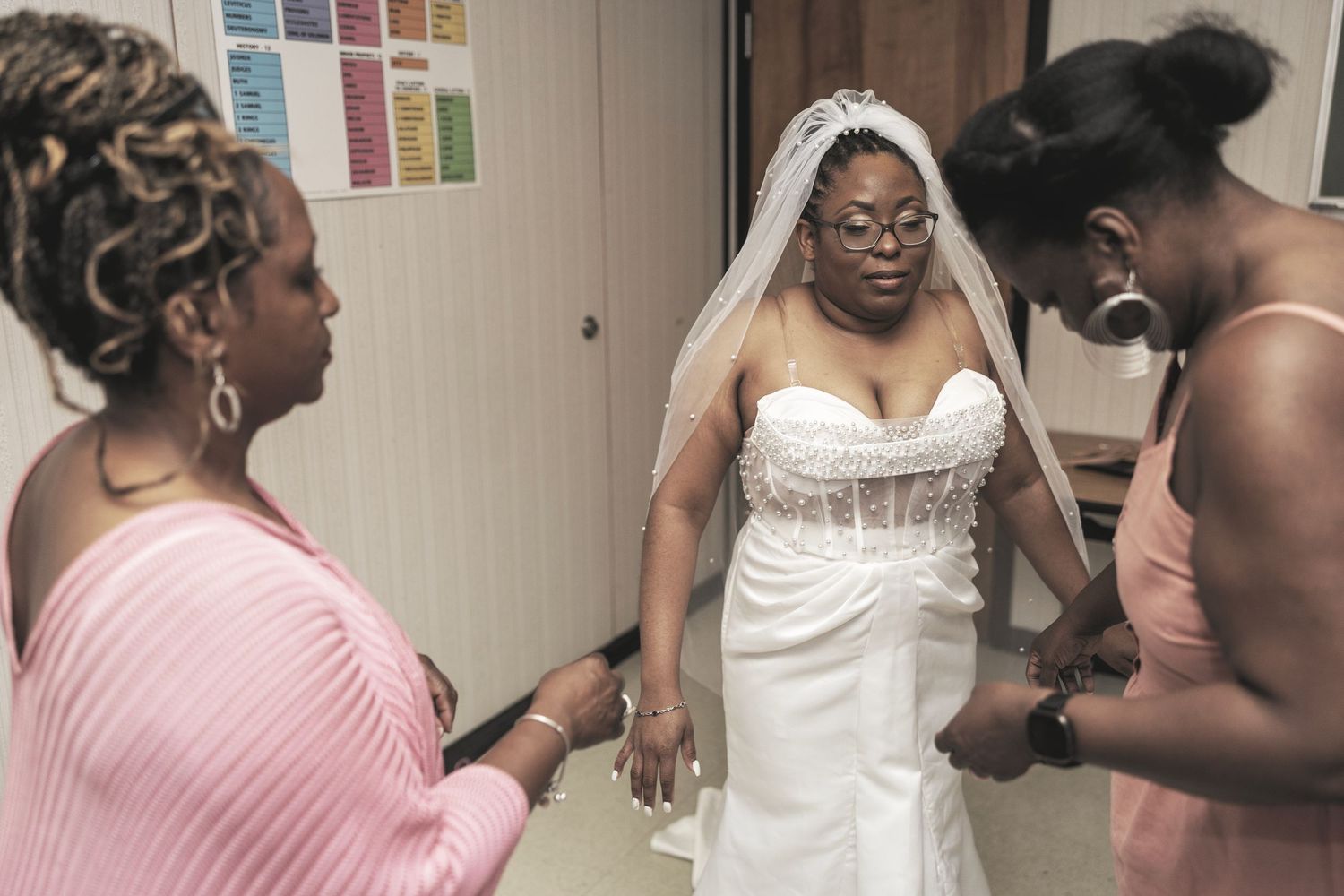 A group of people in formal attire gather together in what appears to be a dressing room or preparation area.