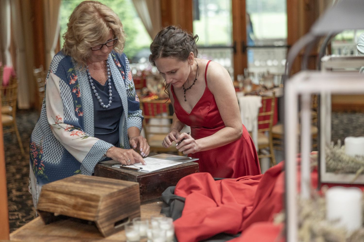Two people sit together at a table working on a craft project with paper and supplies.