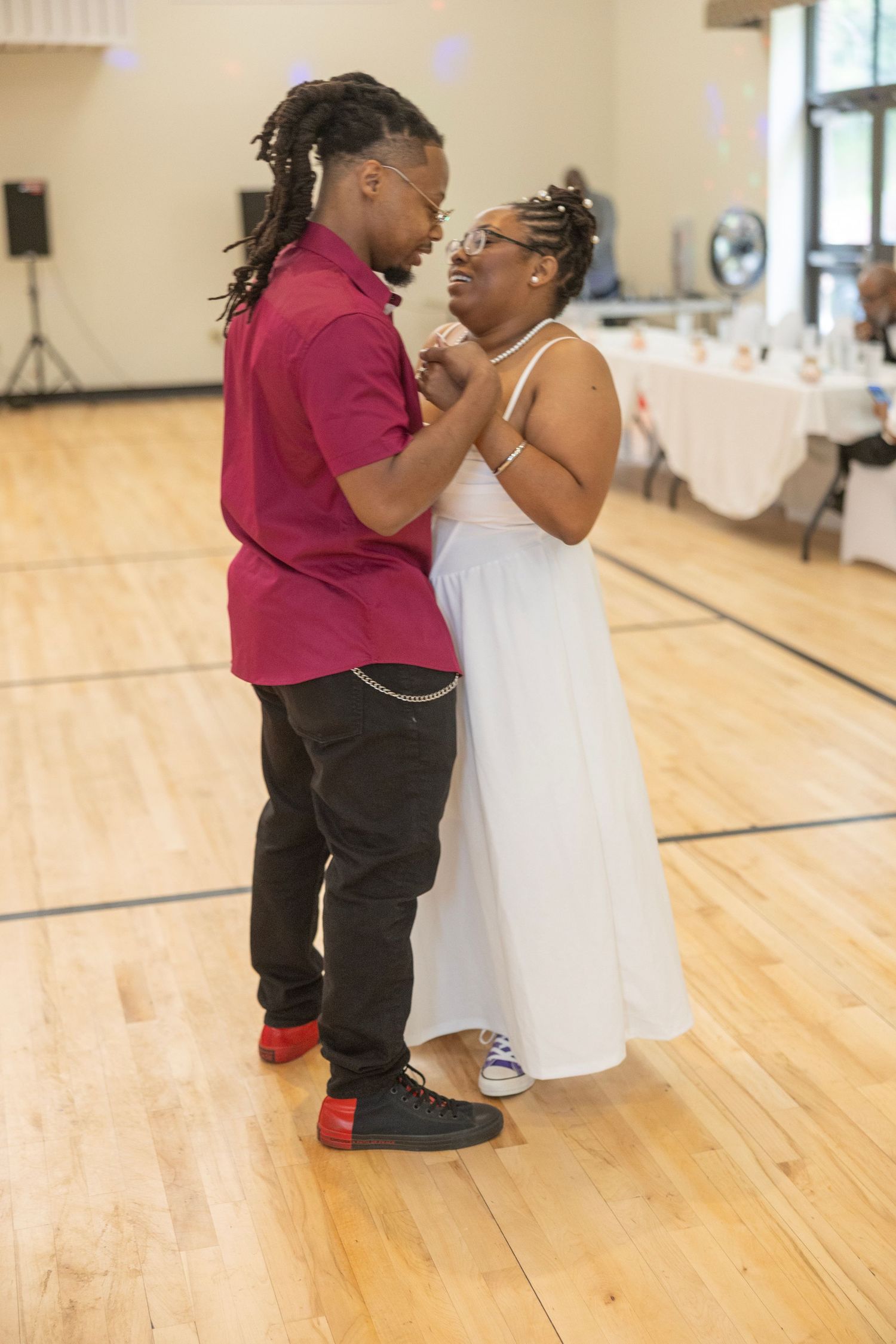 A couple dances together in a studio with wooden floors, creating a heartwarming moment.