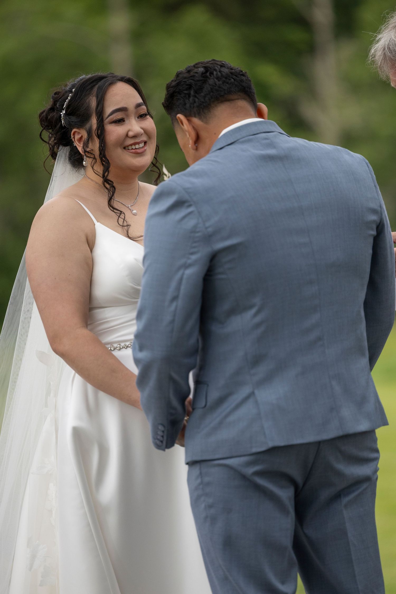 A bride and groom share a joyful moment during their outdoor wedding ceremony.