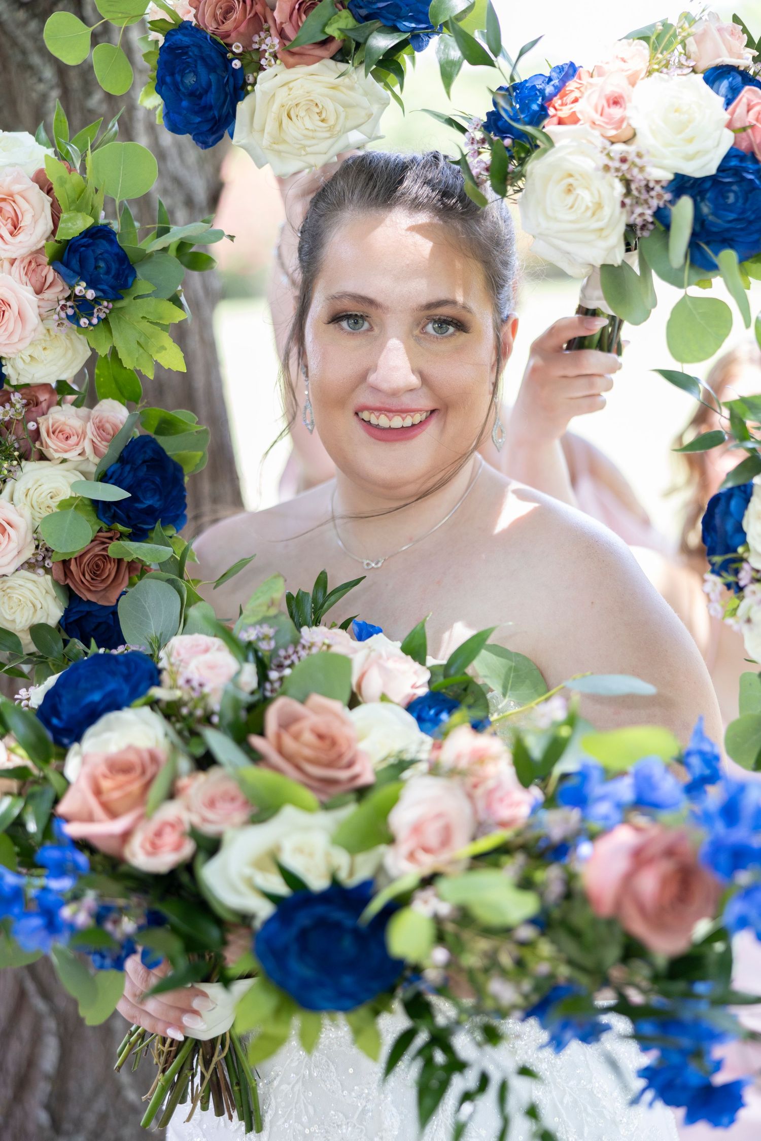 Wedding bouquet featuring pink roses, vibrant blue flowers and fresh green eucalyptus leaves arranged in romantic style.
