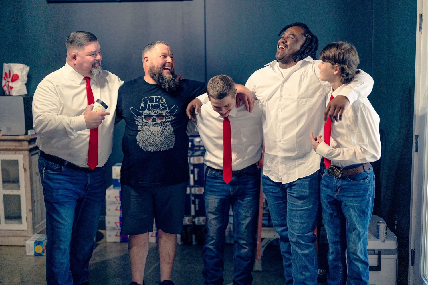 A group of coworkers in business attire laugh and interact during a casual workplace gathering.