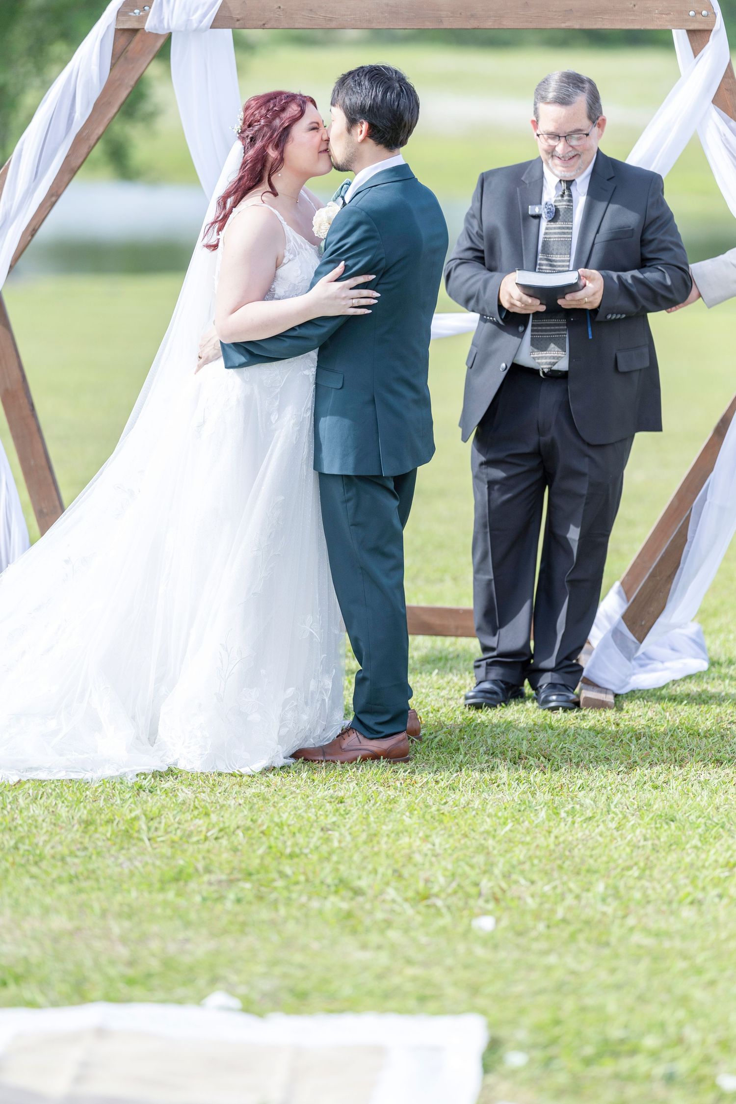 Outdoor wedding ceremony on a grassy lawn with white fabric draping and guests gathered for an intimate celebration.