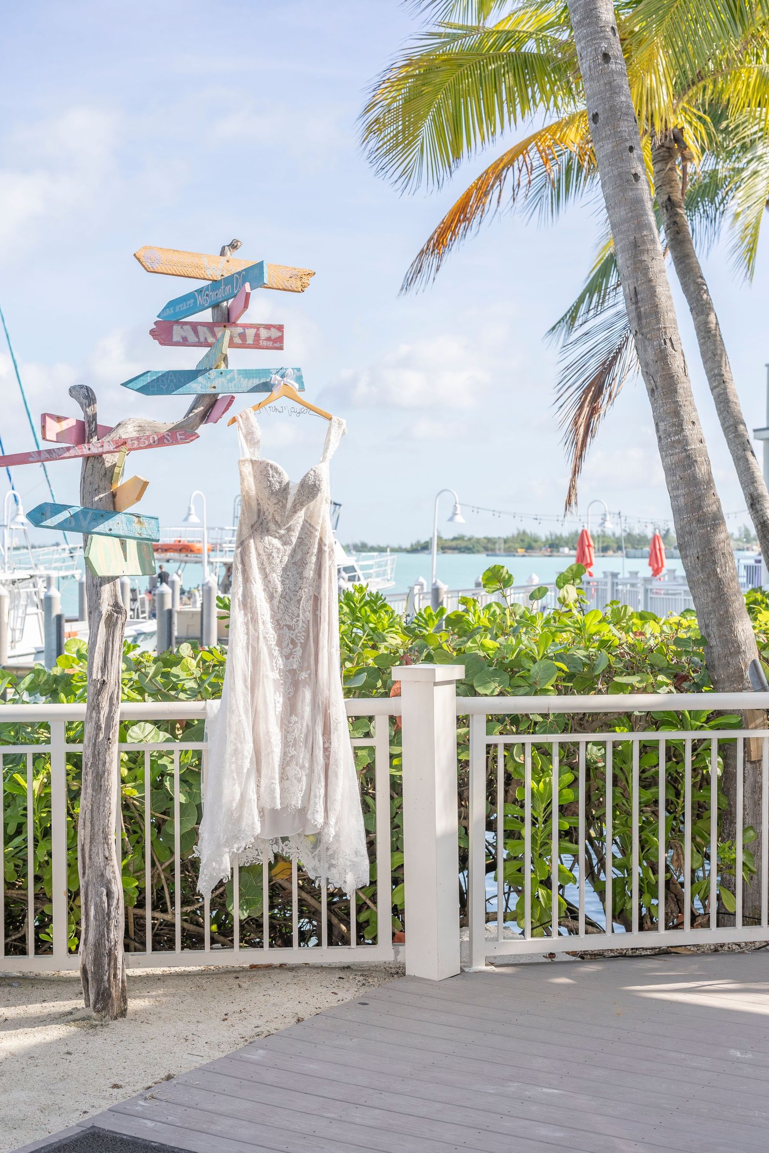 Tropical deck with palm trees and colorful surfboard signs pointing in different directions along white railing.