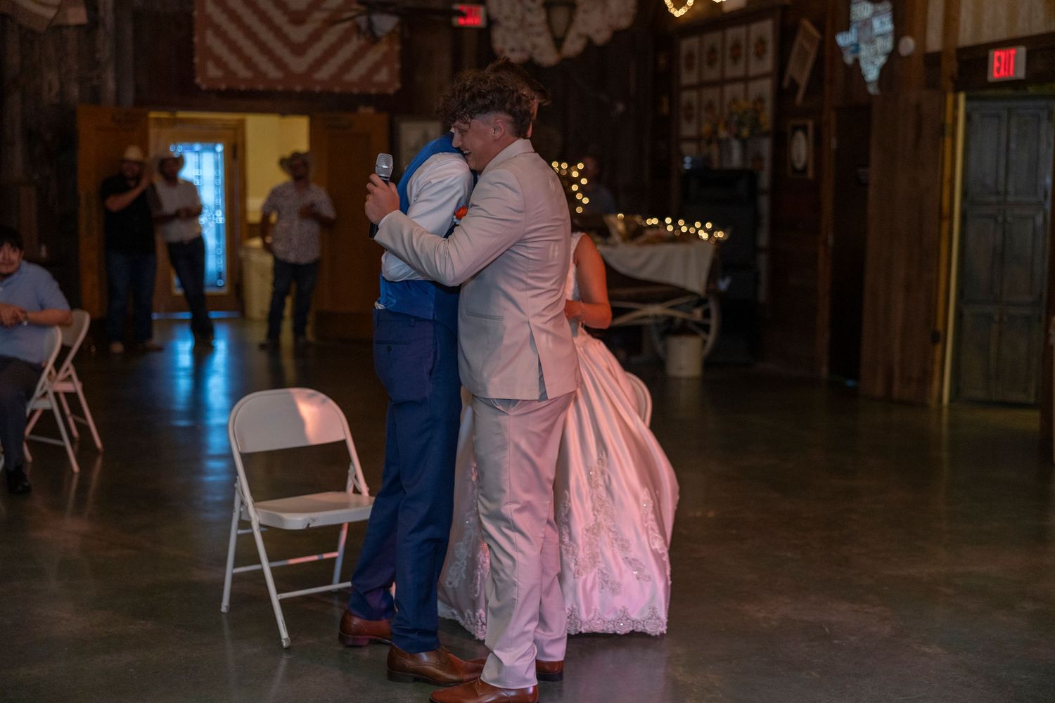 Couple sharing first dance in rustic barn wedding venue with warm string lights and wooden decor.