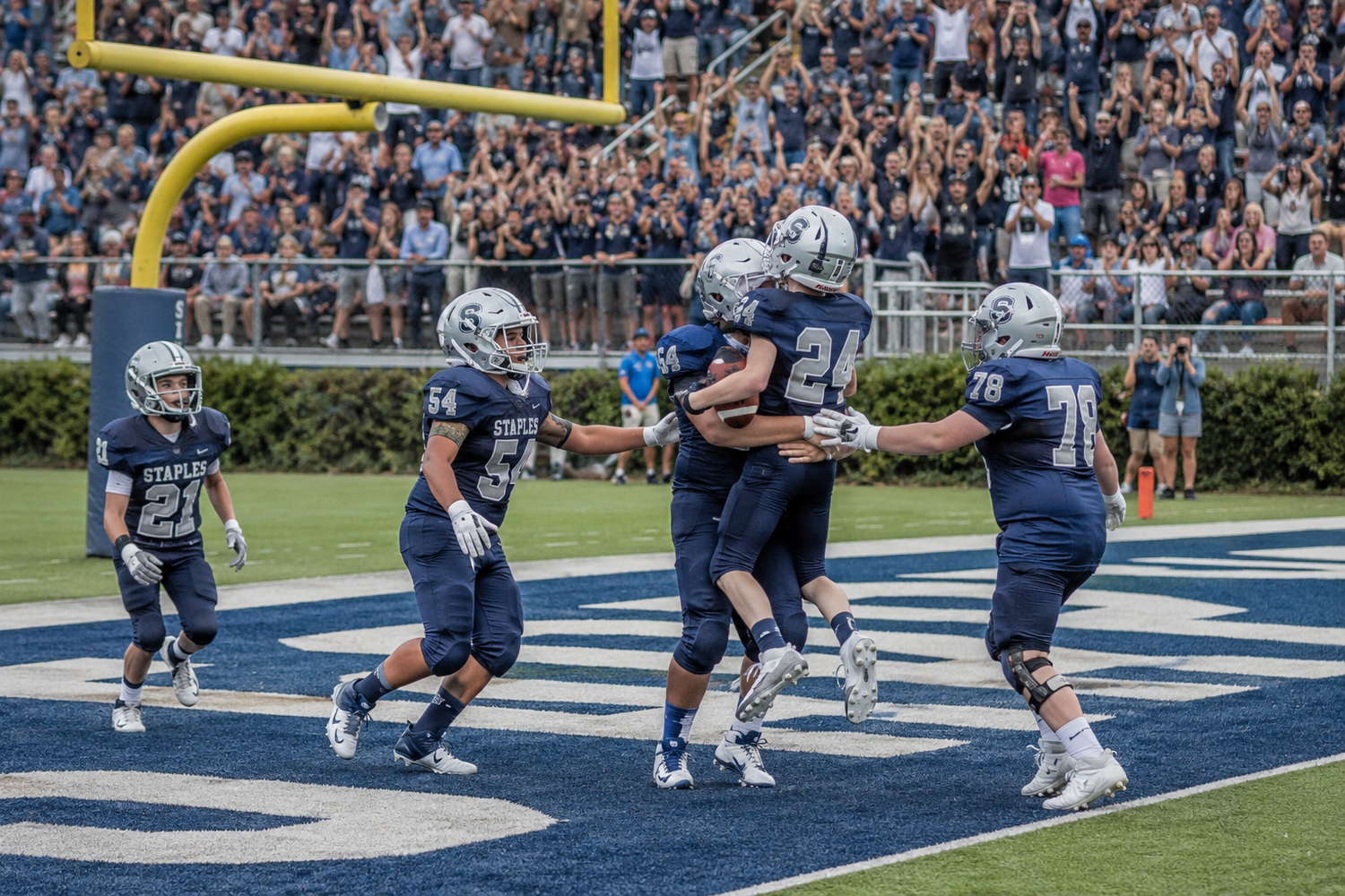 Football players celebrating a touchdown in the end zone during a competitive college football game.