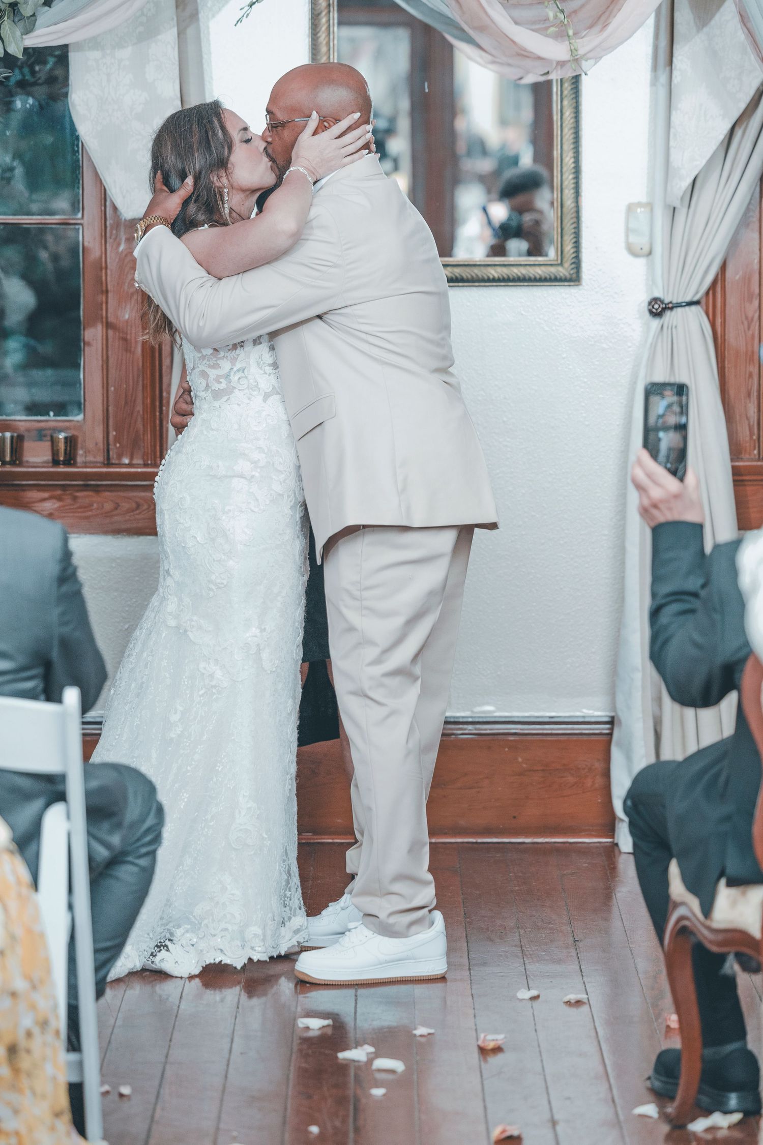 A couple shares their first dance at their wedding reception, with the bride in white lace and groom in light colored suit.