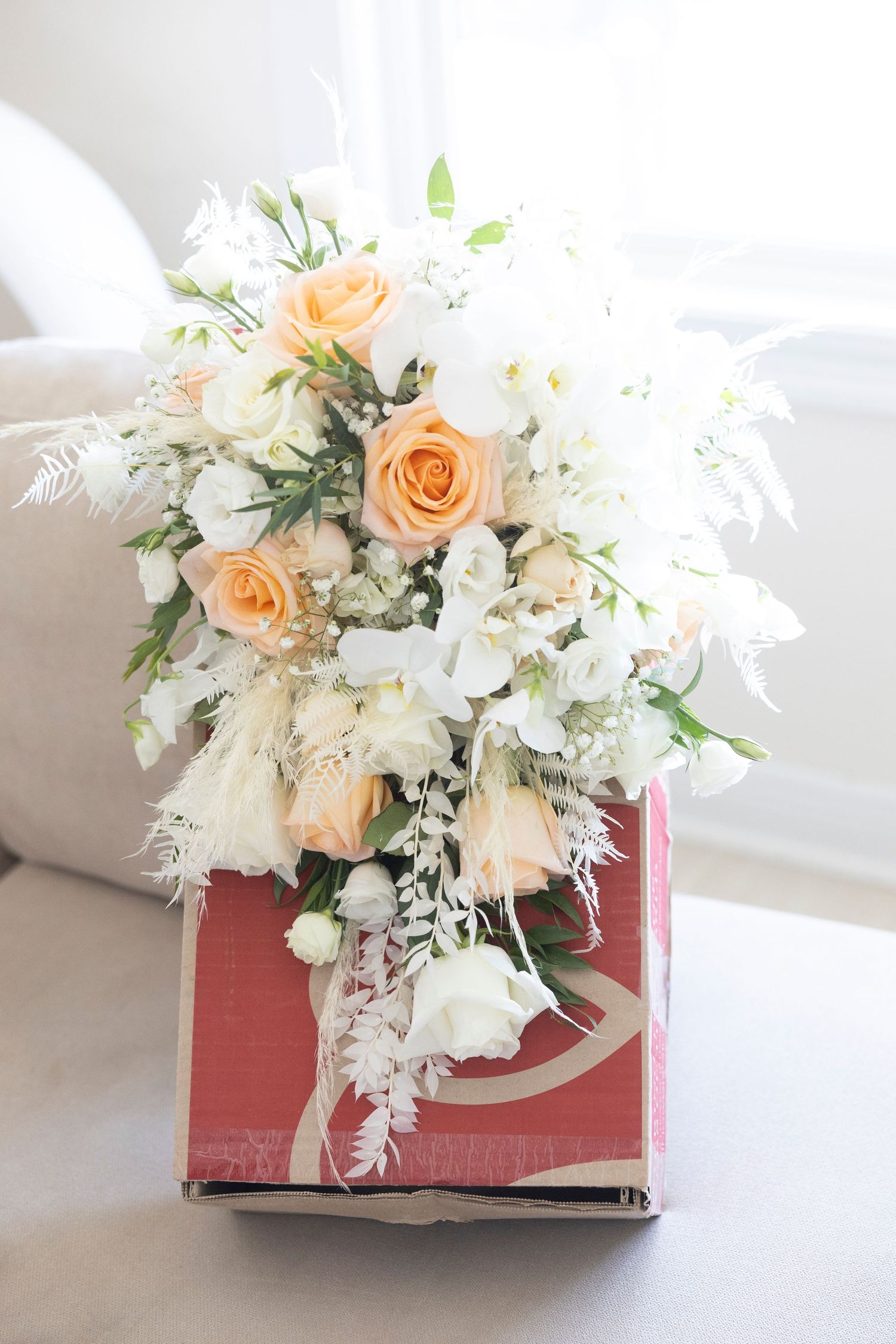 Elegant floral arrangement with peach roses and white flowers displayed in a red book as a creative vase centerpiece.