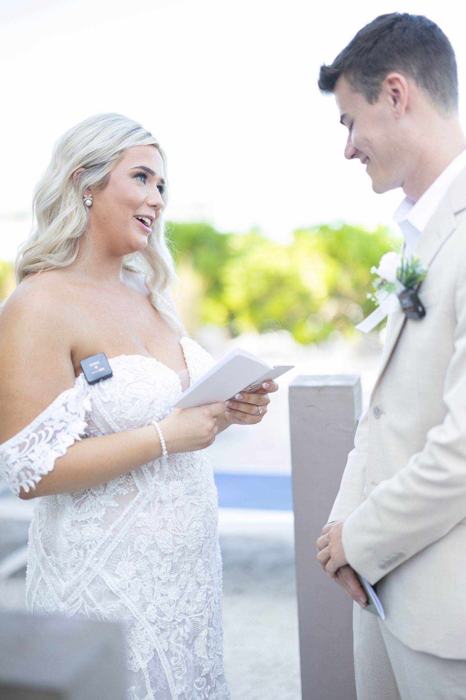 A bride and groom share a joyful moment reading letters to each other during their outdoor wedding ceremony.