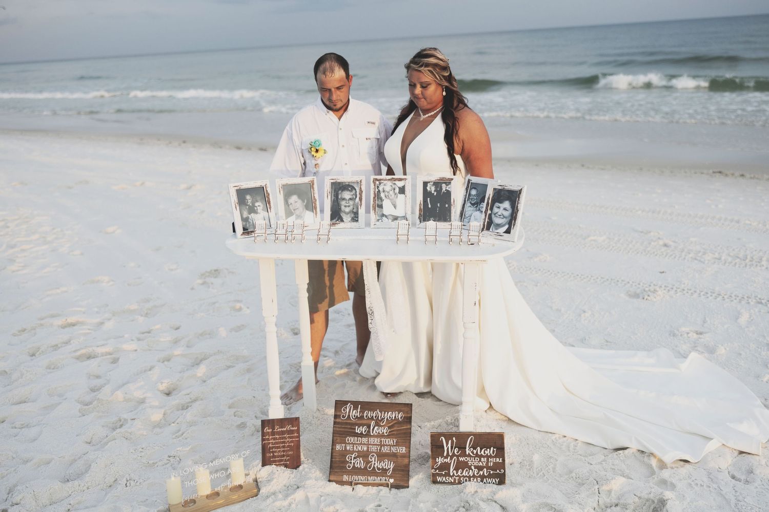 A romantic beach wedding setup with white chairs and floral arrangements along a sandy aisle at sunset.