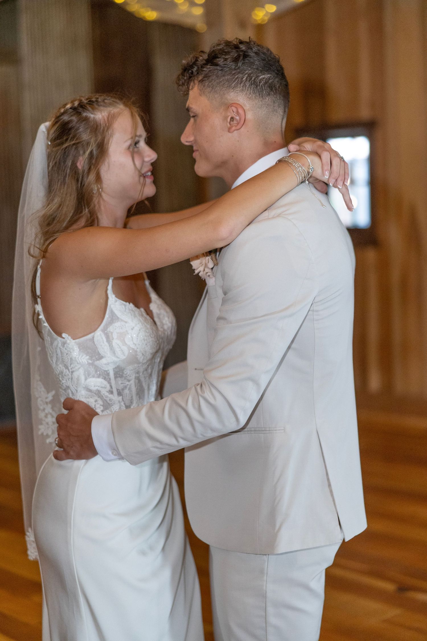 A bride and groom share their first dance together in a warmly lit ballroom.