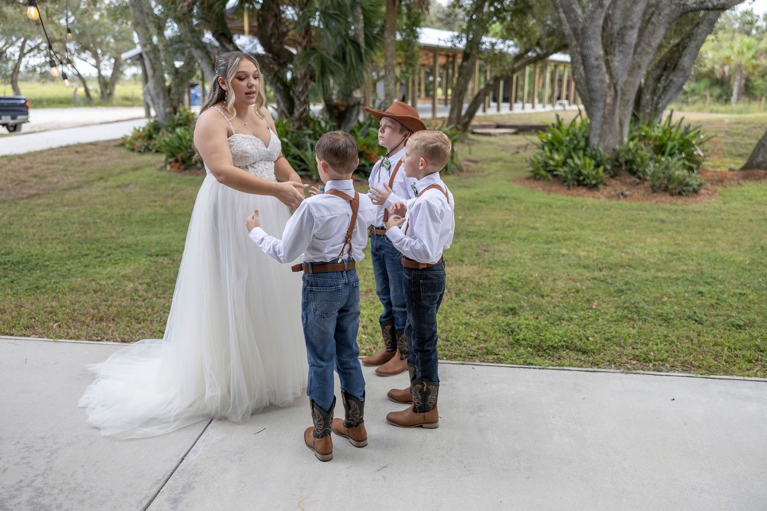 A couple in western attire poses outdoors during a rustic wedding photoshoot with natural scenery in the background.