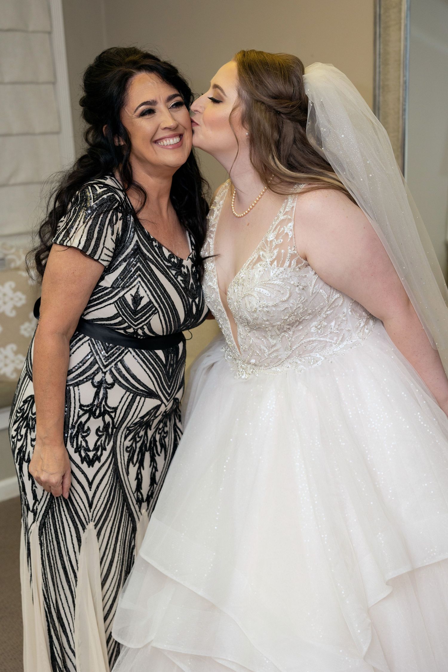 Two people share a sweet moment as one kisses the other's cheek during a wedding celebration.