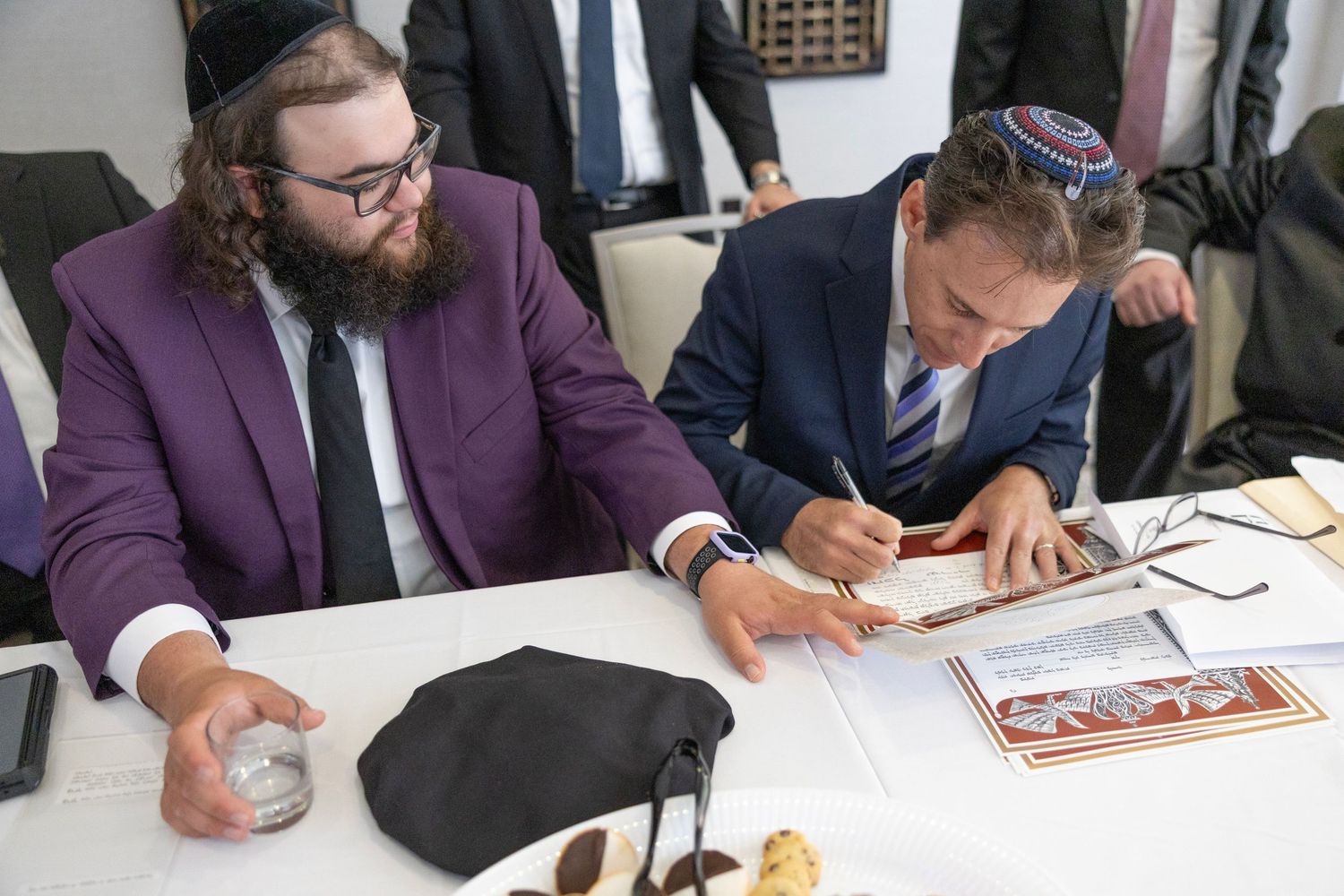 People signing documents at a conference table in a business meeting setting.