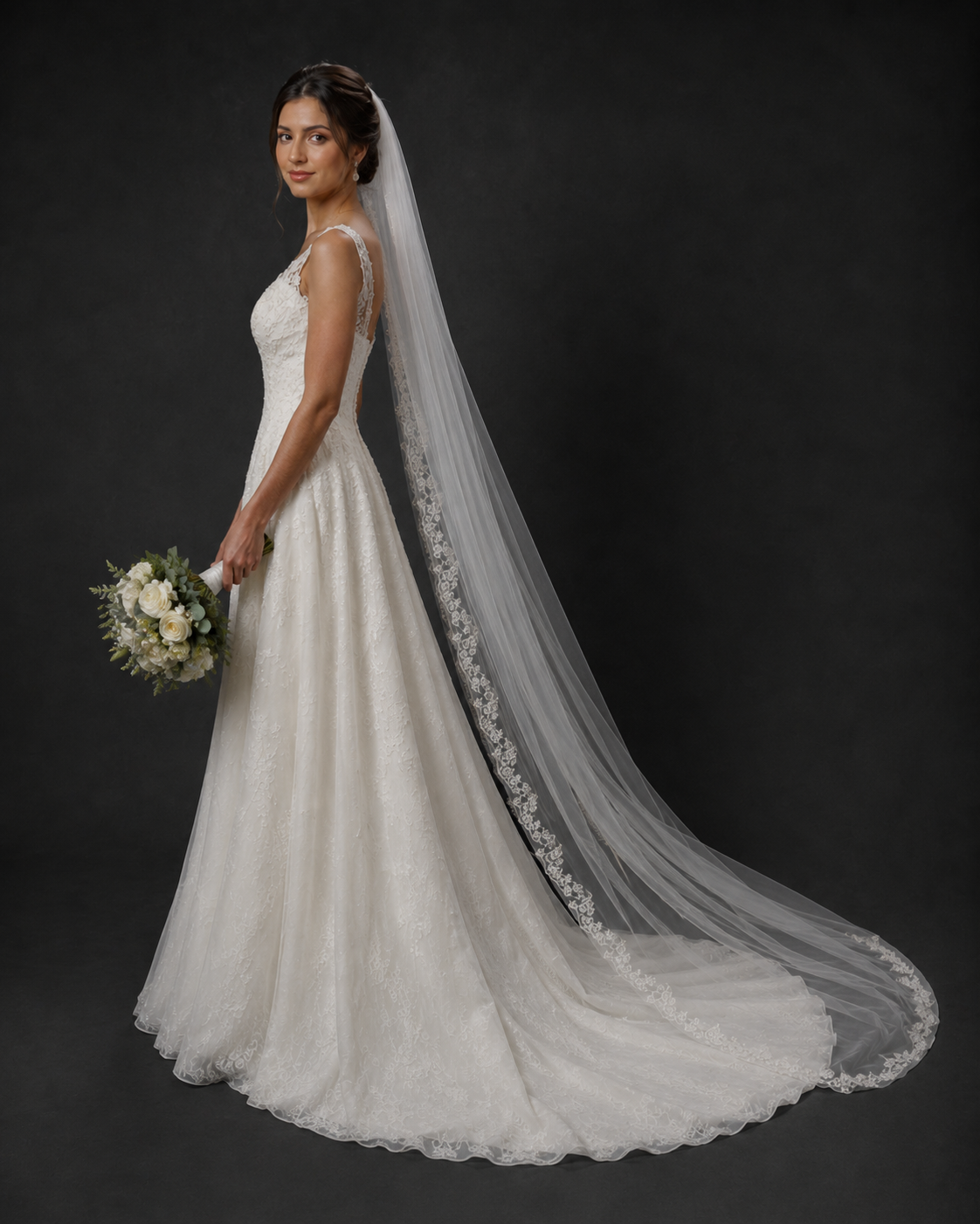Bride in a white lace A-line gown with a long floral-edged cathedral veil, holding a white bouquet.