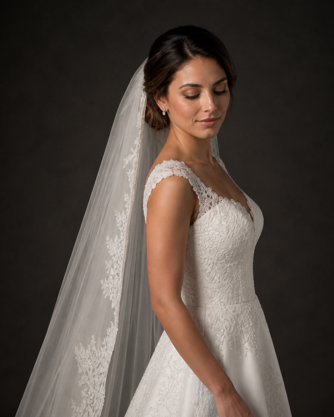 Bride wearing a lace A-line wedding gown with cap sleeves and a long flowing veil, posing elegantly.