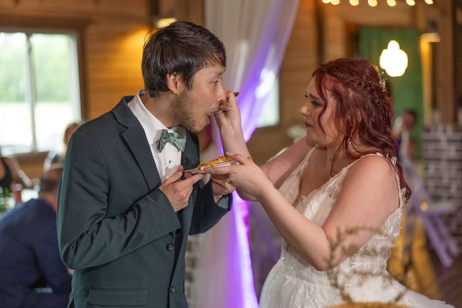 A couple shares their first dance together at a wedding reception in a warmly lit rustic venue.