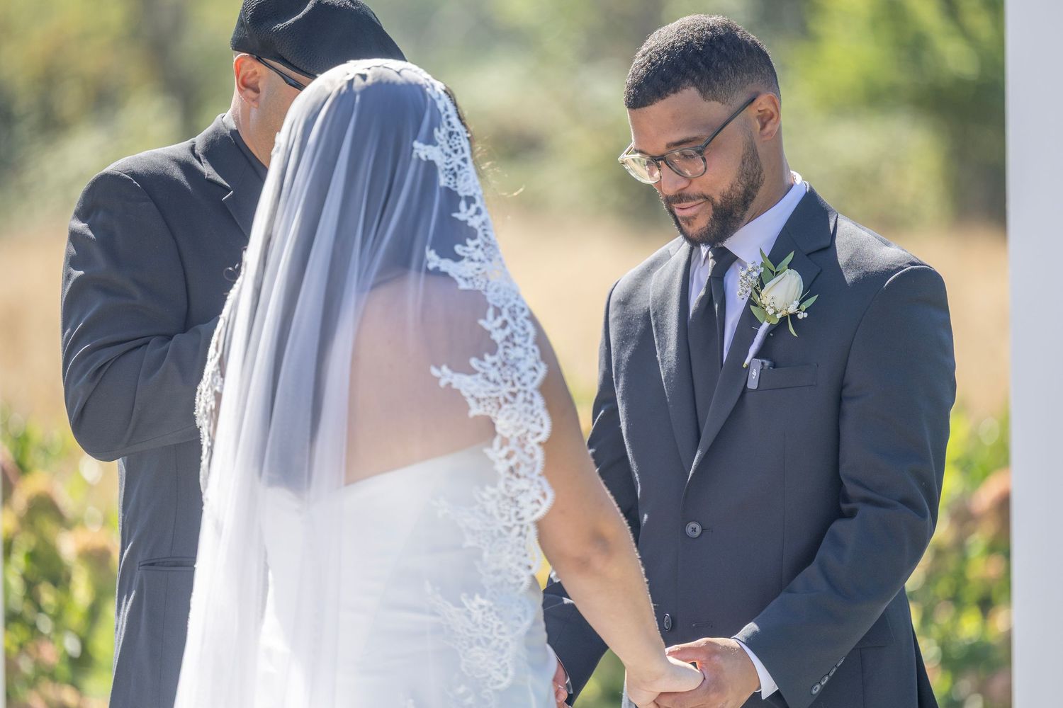 A couple shares an intimate moment during their outdoor wedding ceremony in a garden setting.