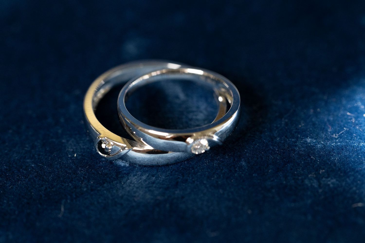 Close-up macro photography of a diamond engagement ring on dark blue velvet background.