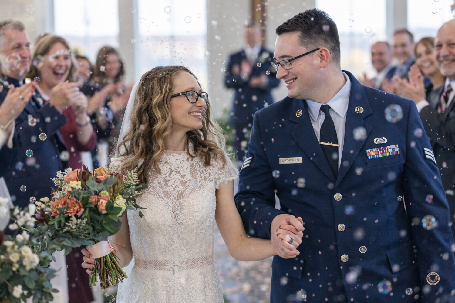 A couple shares a joyful moment during their wedding ceremony as bubbles float around them in an indoor venue.