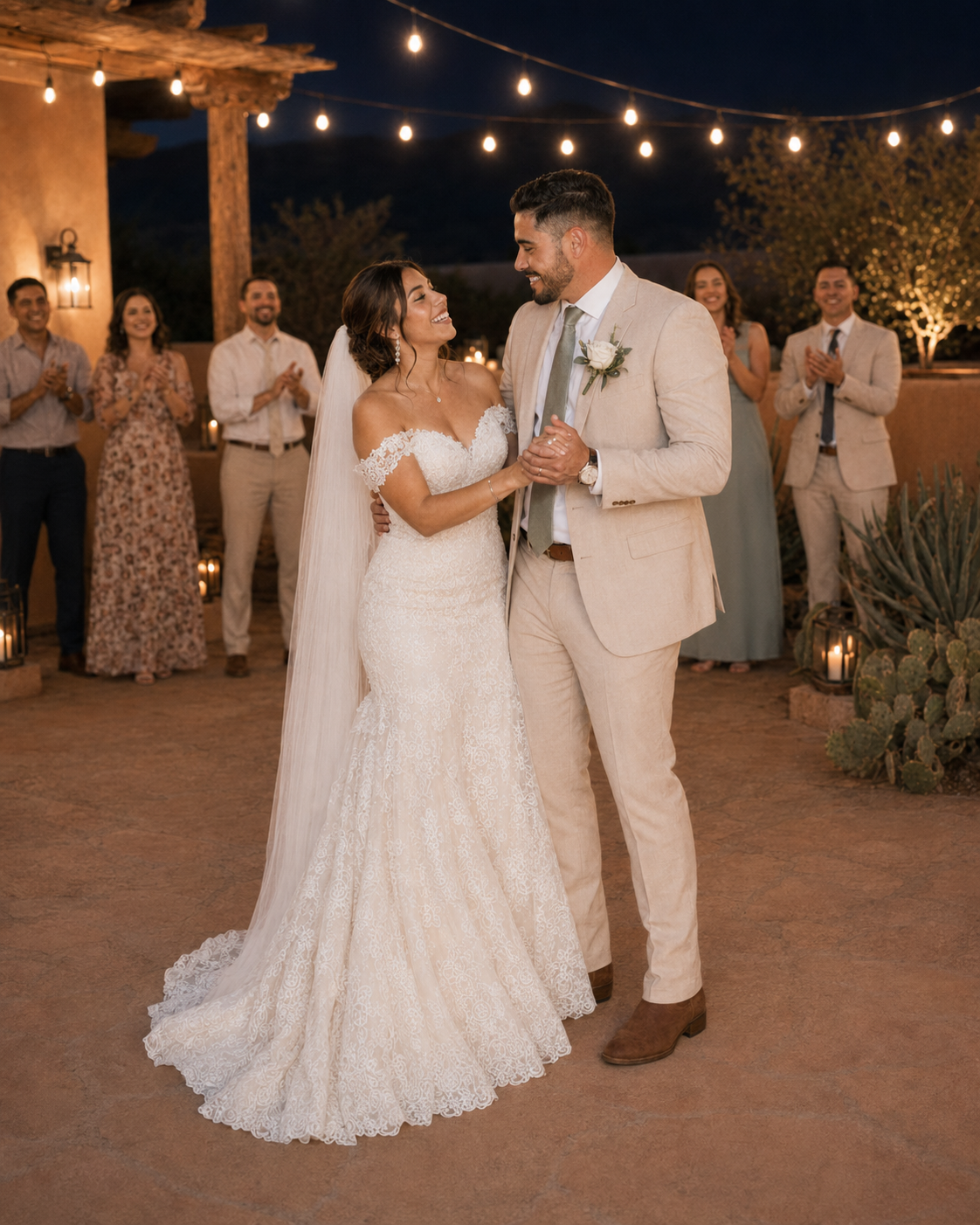 Bride and groom share first dance outdoors at night under string lights with wedding guests applauding around them.