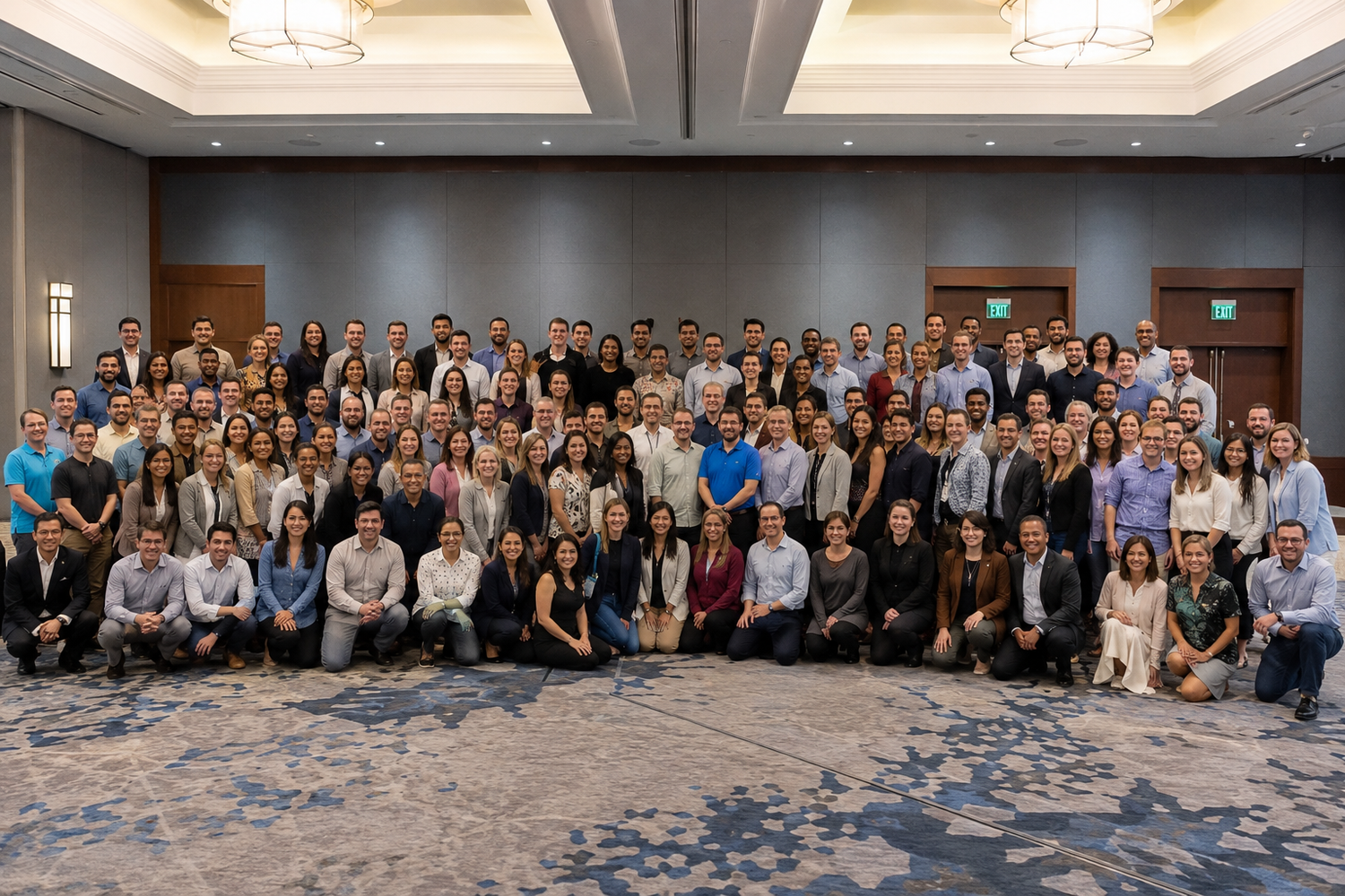 Large professional group photo of diverse colleagues posing together in a modern conference hall.