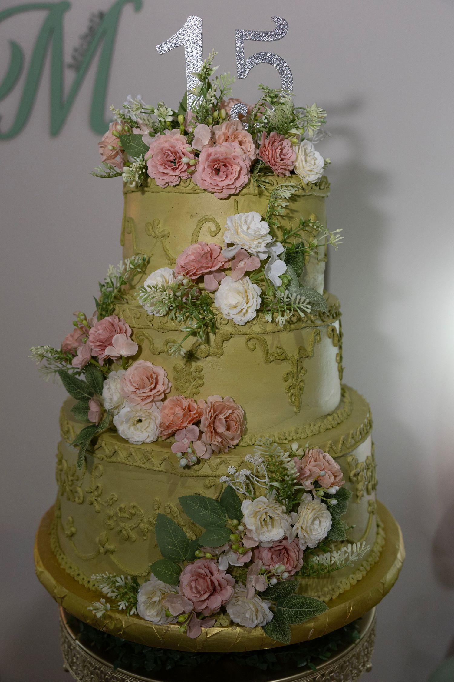 Elegant wedding cake decorated with delicate pink roses and white flowers against a soft green fondant background.