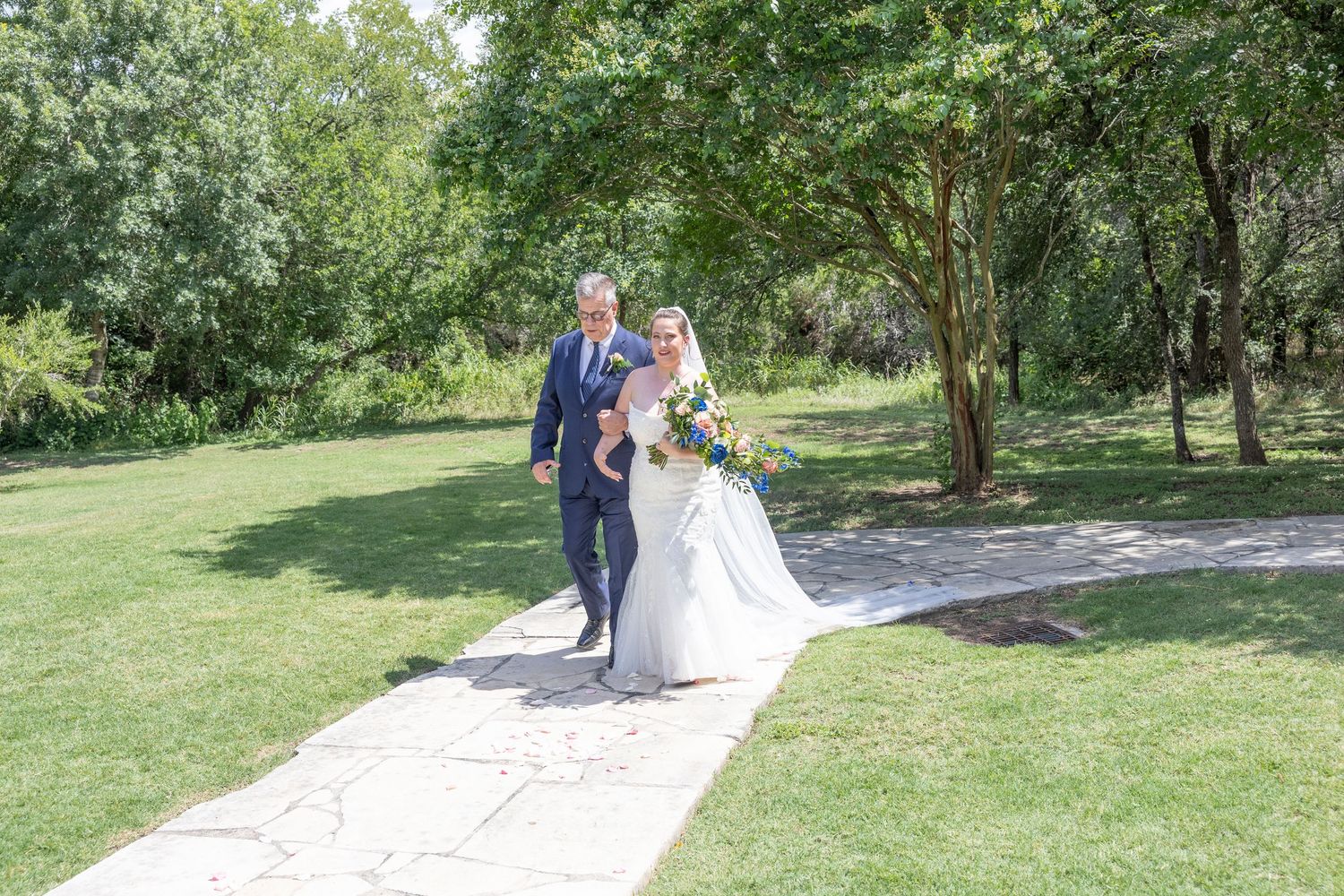A couple in wedding attire walks together along a scenic garden path on their special day.