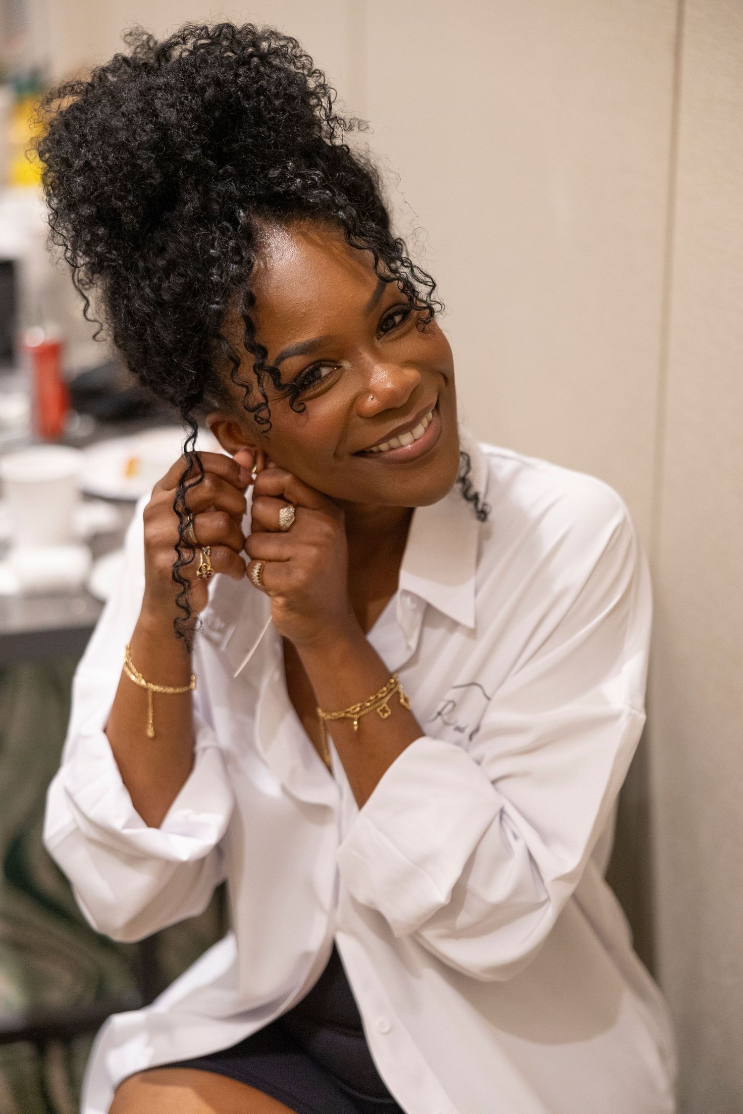 A series of joyful portrait shots showing natural curly hair and a crisp white button-down shirt against a light background.